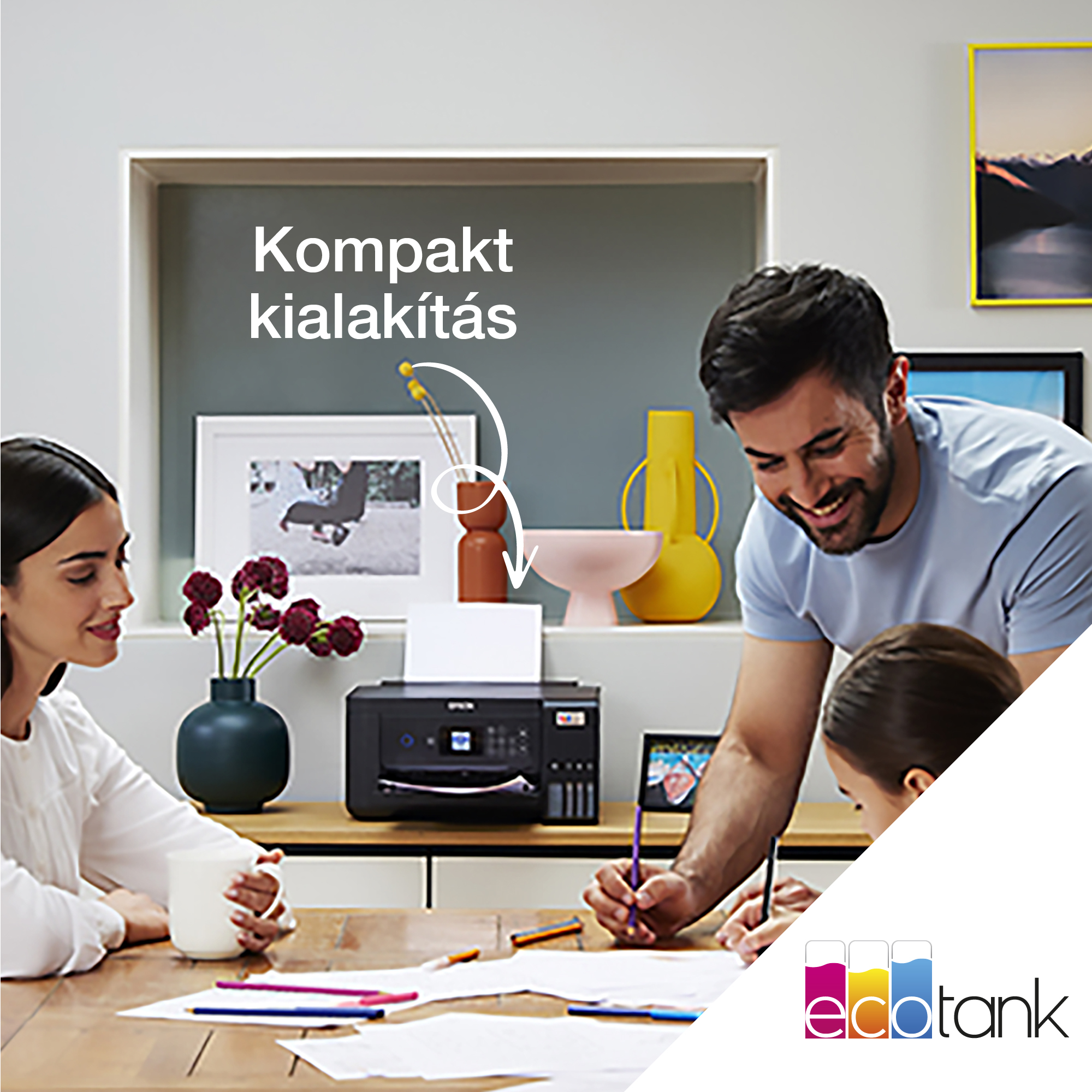 Egy család az asztalnál. Egy férfi és egy lány rajzol. Egy nő egy csészét tart. Egy nyomtató az asztalon van.