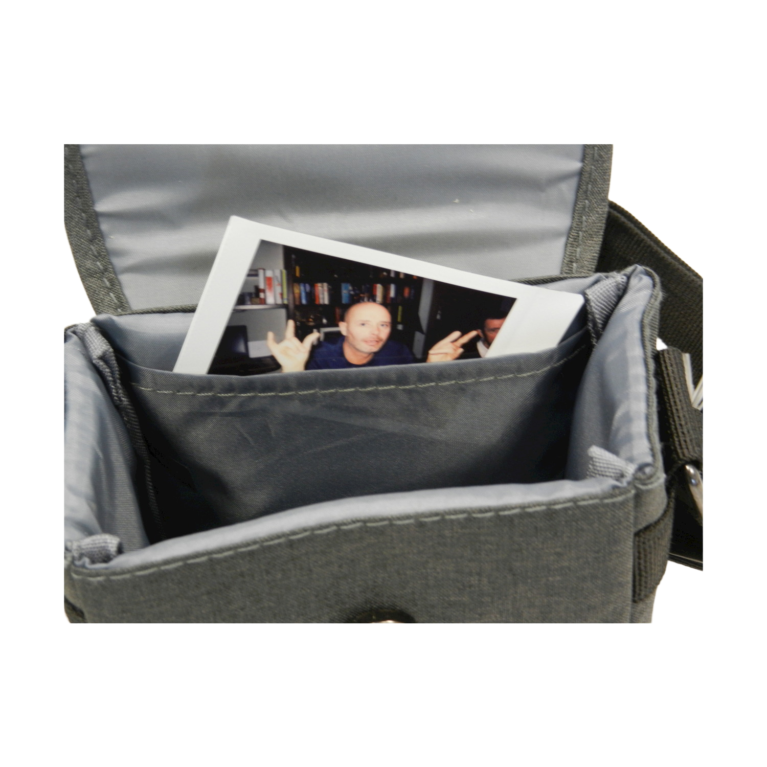 Una borsa grigia per fotocamera con una foto di un uomo all'interno. La foto mostra un uomo che fa gesti con le mani. La borsa è aperta.
