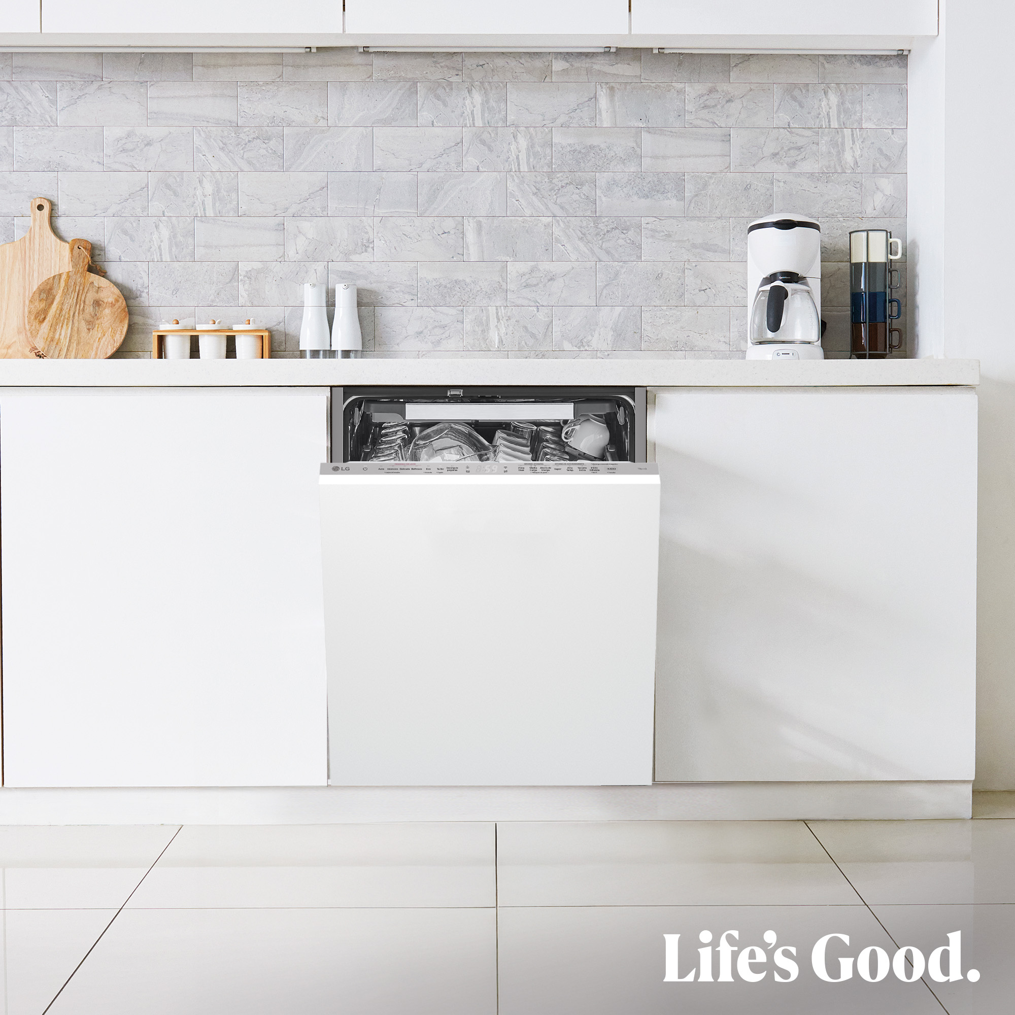 Escena de cocina con lavavajillas abierto. Gabinetes blancos, salpicadero de mármol, cafetera y logo Life's Good abajo.