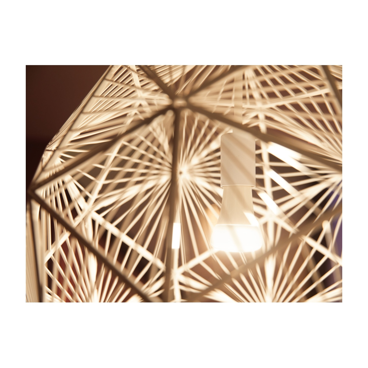 Un primo piano di una lampada decorativa. Ha un design geometrico e una lampadina luminosa all'interno, che proietta ombre.