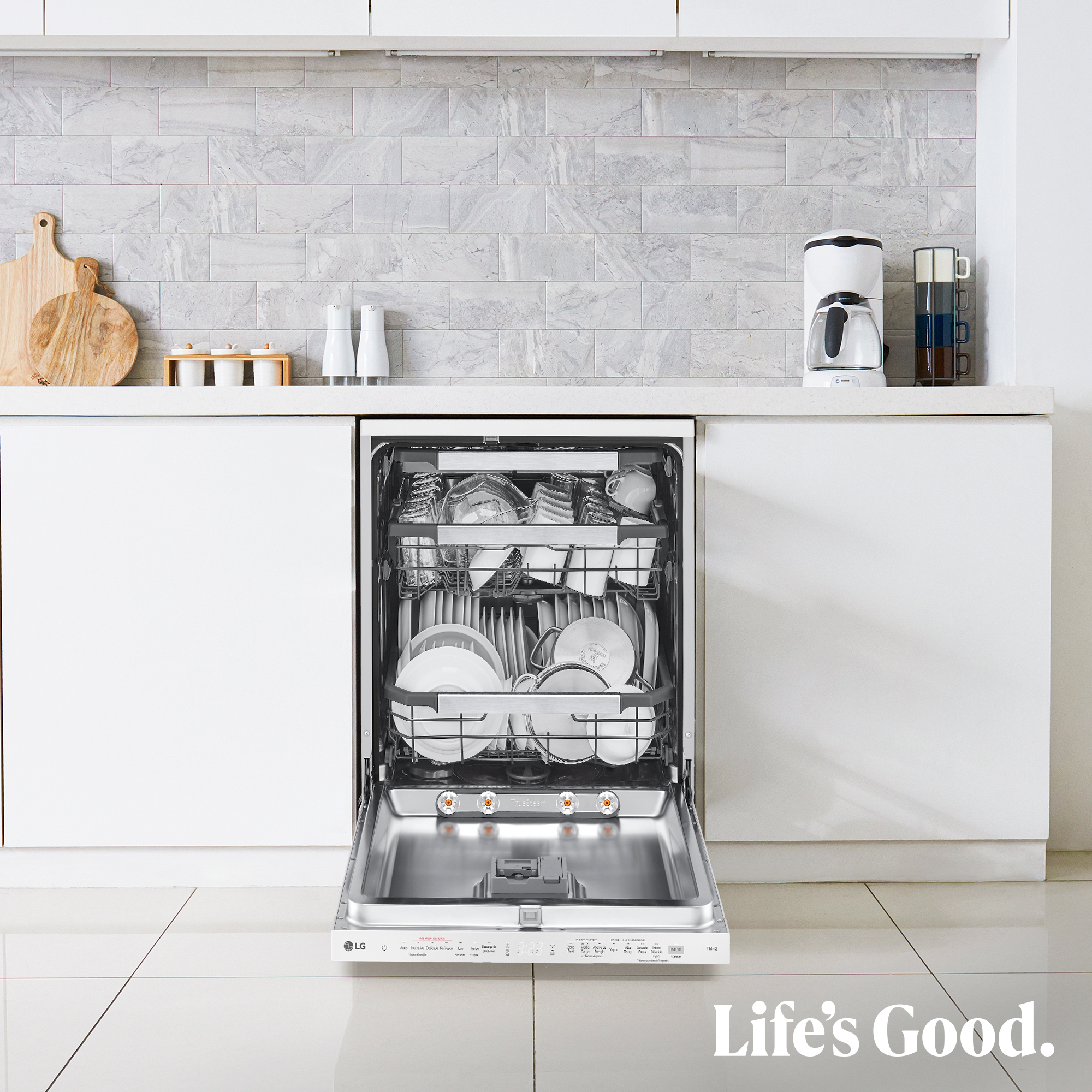 Un lavavajillas abierto, lleno de platos limpios. La cocina tiene gabinetes blancos y un protector contra salpicaduras. Está escrito 'Life's Good'.