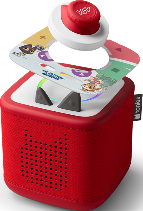 Toniebox rossa con pulsante superiore rosso 'PLAY'. Una carta con personaggi dei cartoni animati è sopra la scatola. La scatola ha fori per altoparlanti.