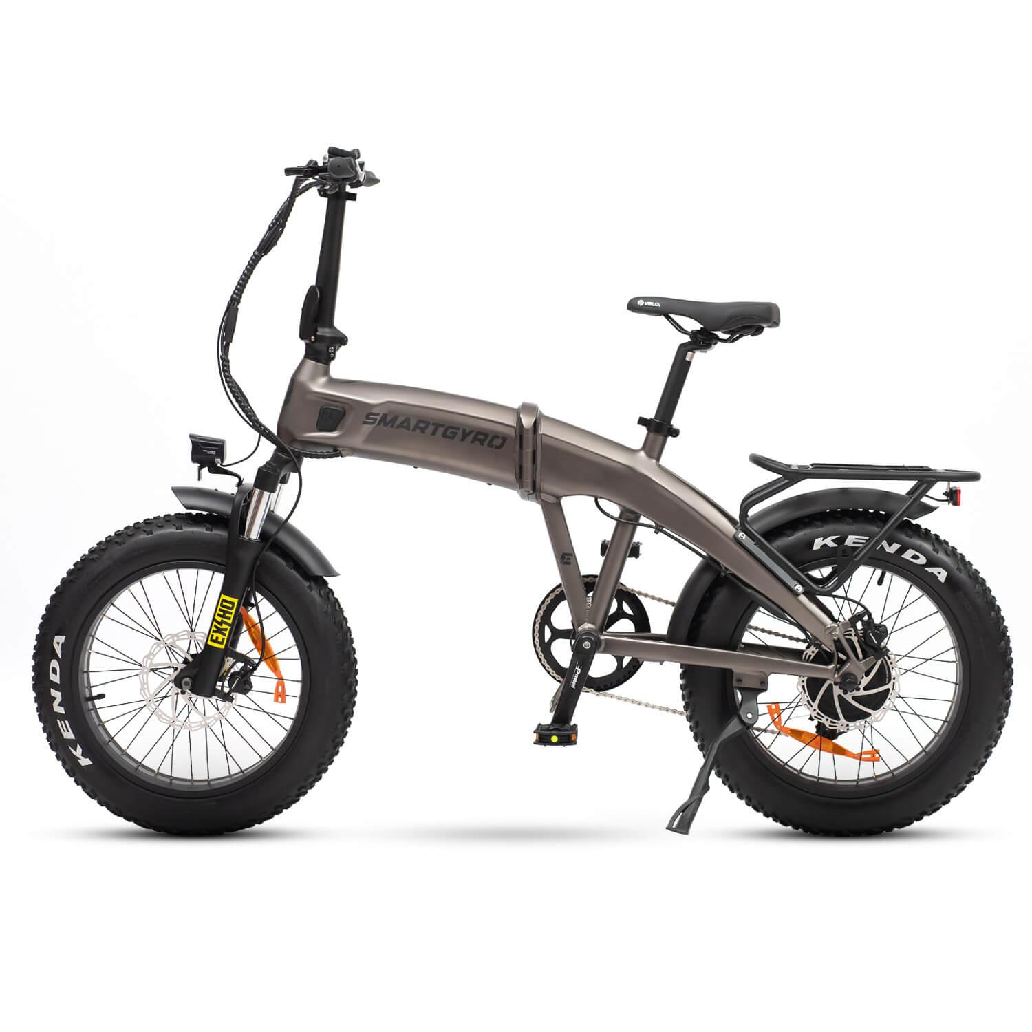 Una bicicleta eléctrica con neumáticos gruesos sobre fondo blanco. Tiene un cuadro gris, neumáticos negros y la marca es Smartgyro.