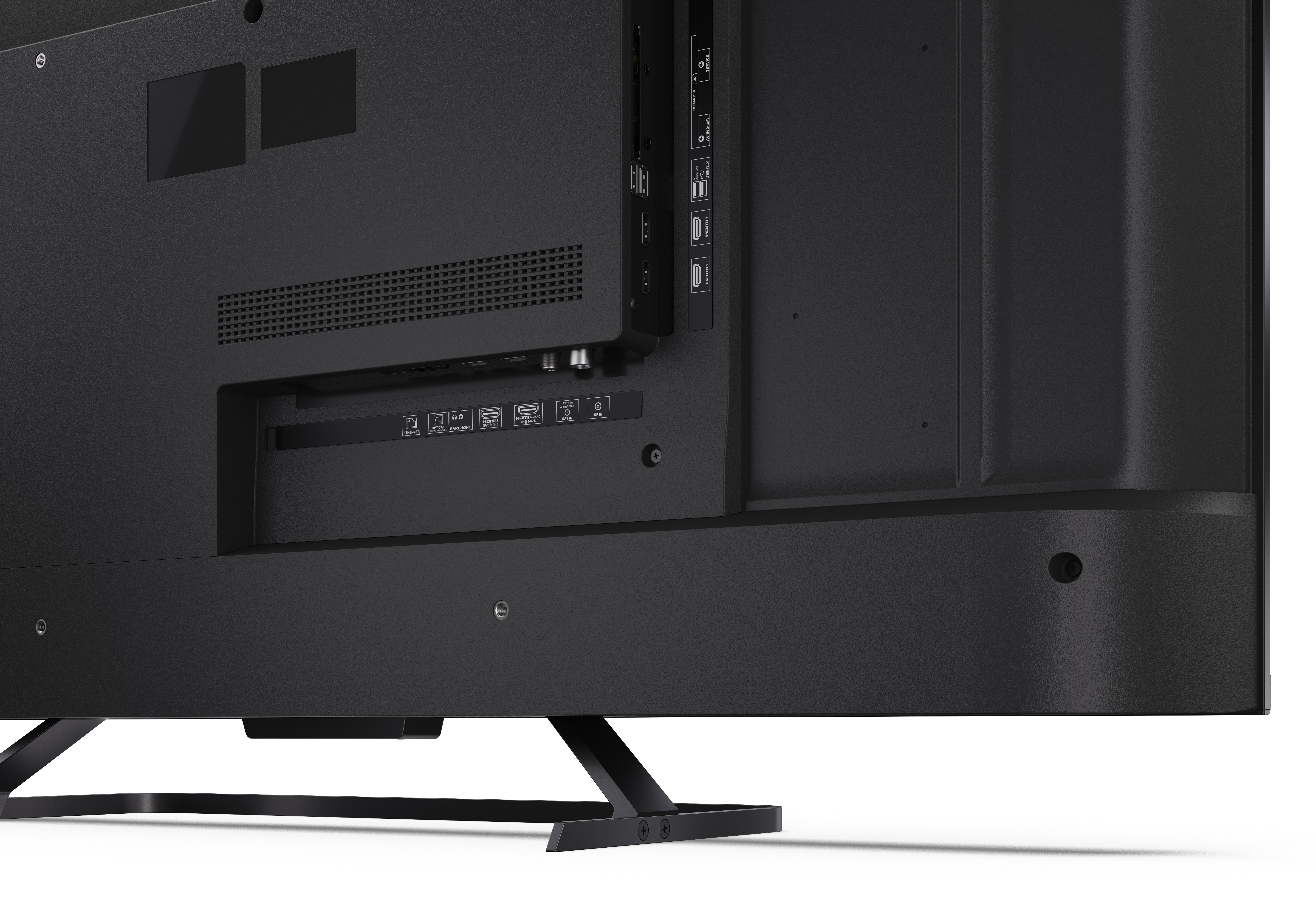 Zbliżenie tylnego panelu czarnego telewizora z portami, w tym HDMI, USB i wejściami audio. Telewizor stoi na czarnym stojaku.