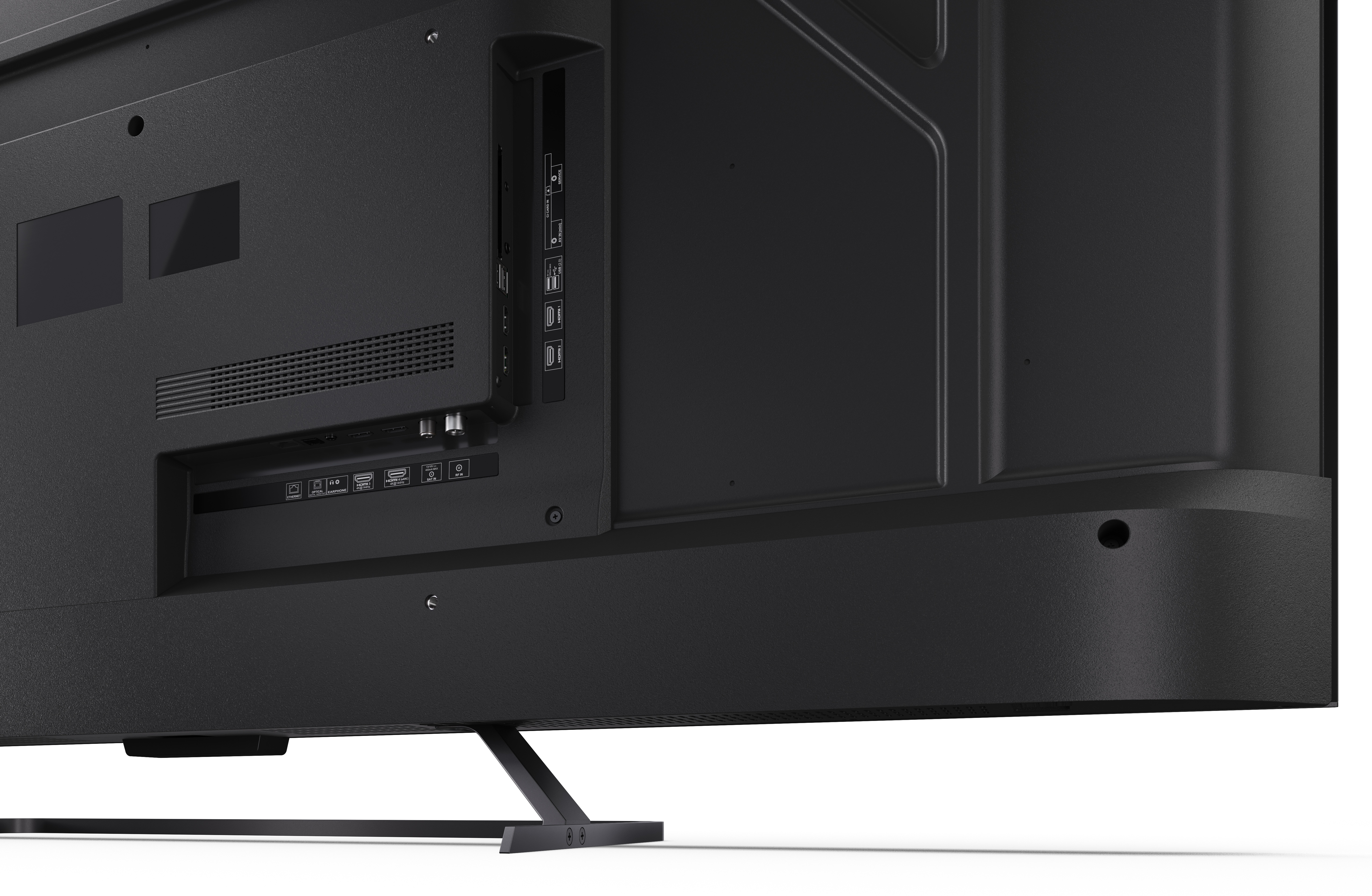 Tył czarnego telewizora pokazuje porty, otwory wentylacyjne i stojak. Telewizor stoi na białej powierzchni.