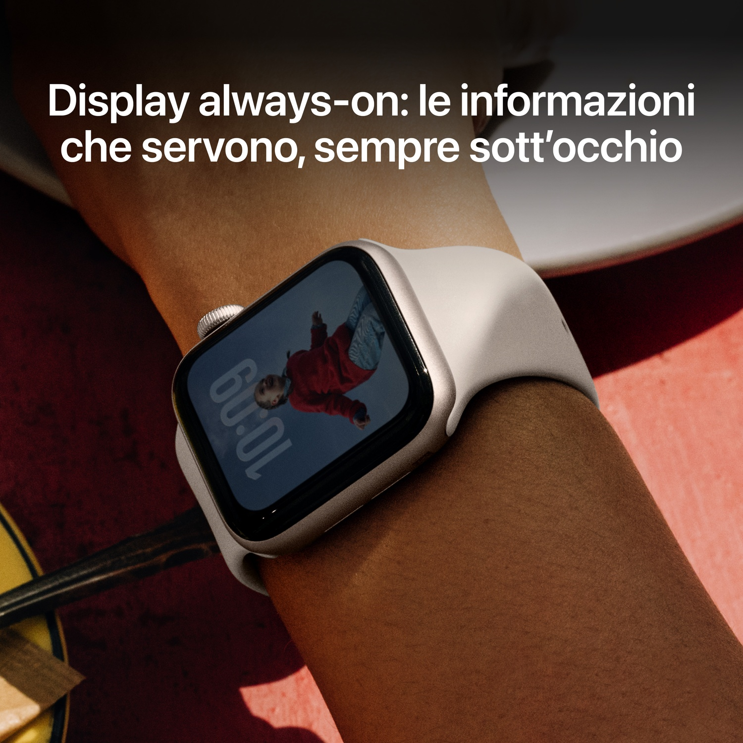 Polso con smartwatch. Il quadrante mostra una persona in rosso e l'ora. Il cinturino è bianco.