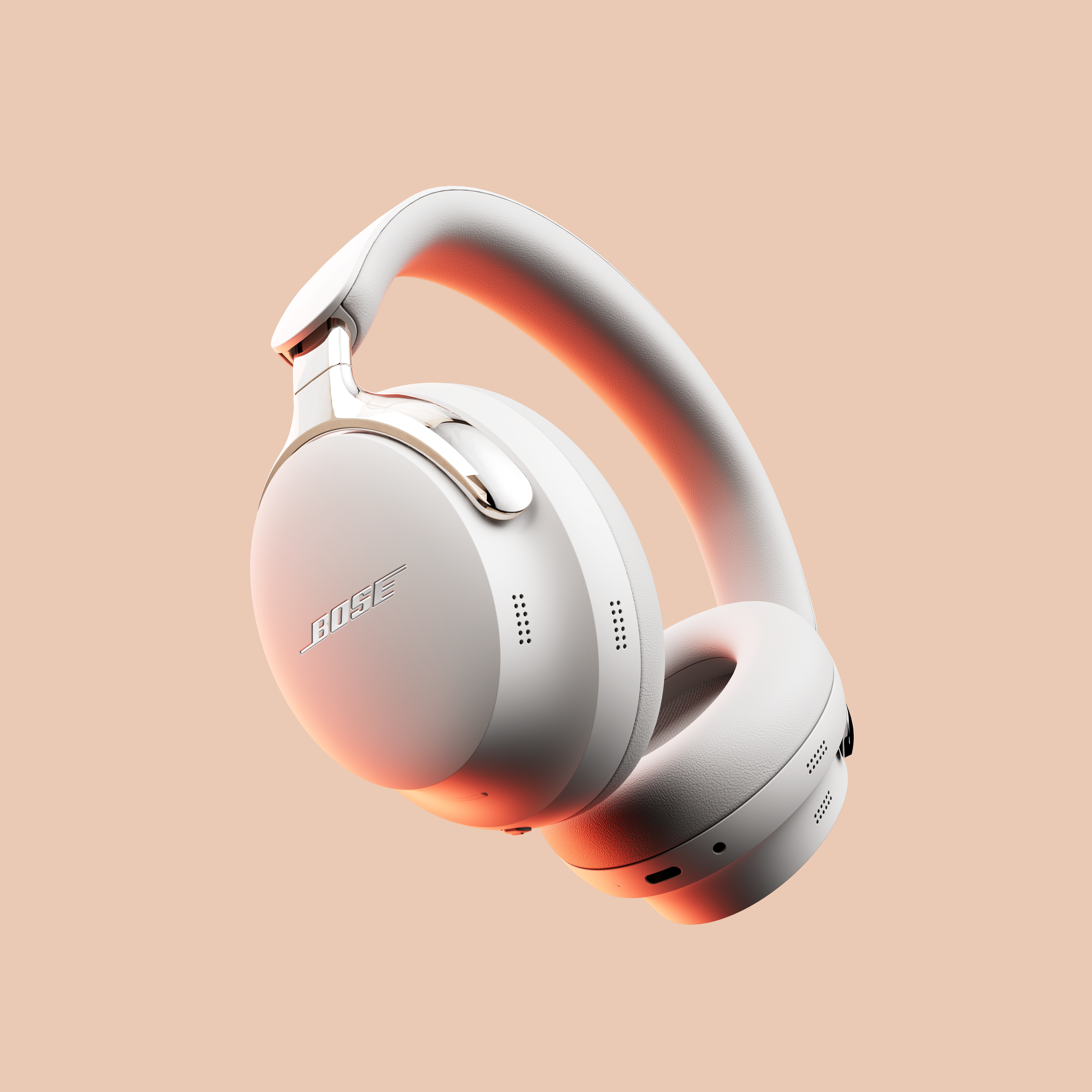 Cuffie Bose bianche su sfondo beige. Le cuffie sono angolate, mostrando il logo del marchio e i padiglioni.