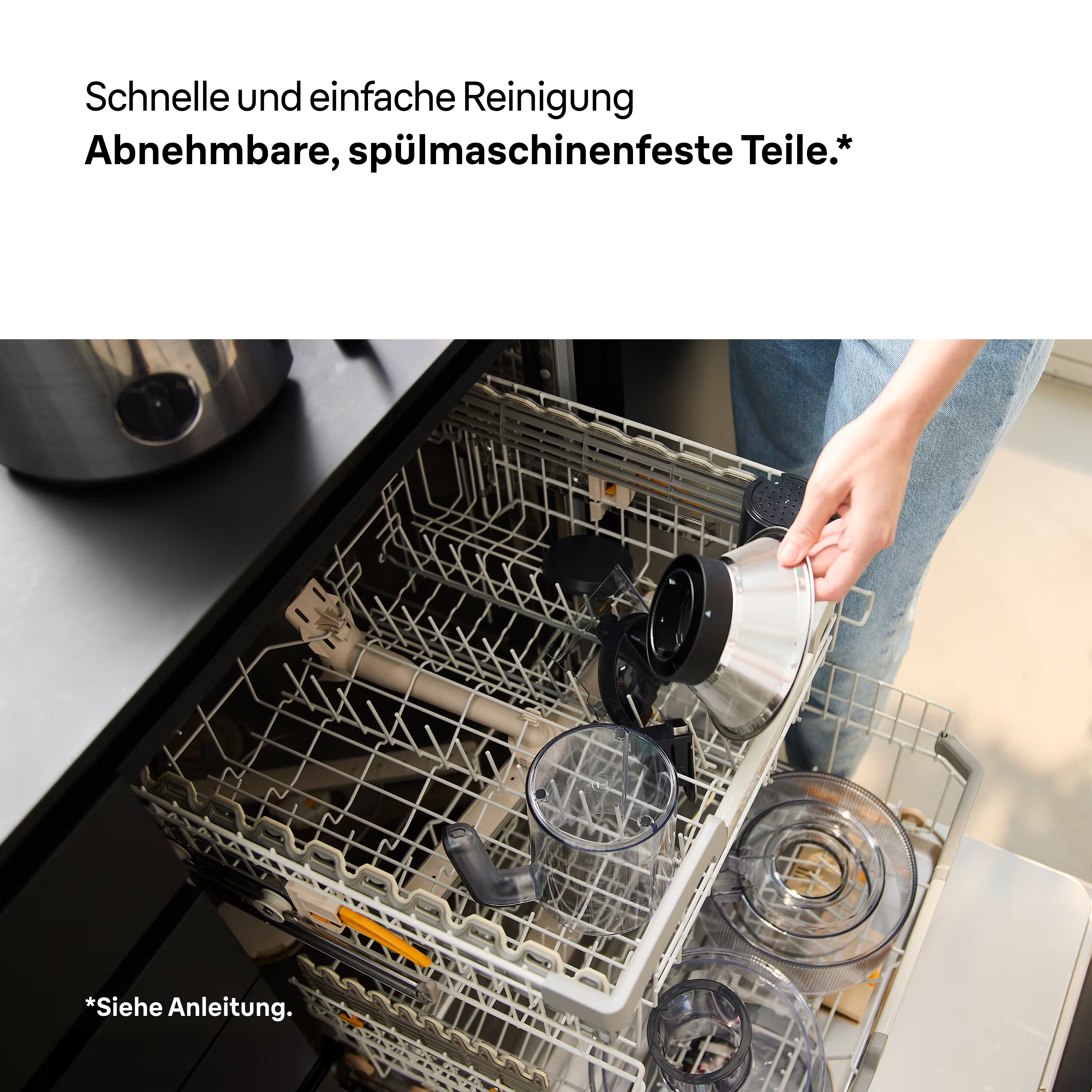 Eine Person legt Küchenmaschinenteile in die Spülmaschine. Teile sind schwarz und silber. Text: 'Einfache Reinigung, spülmaschinenfest'.