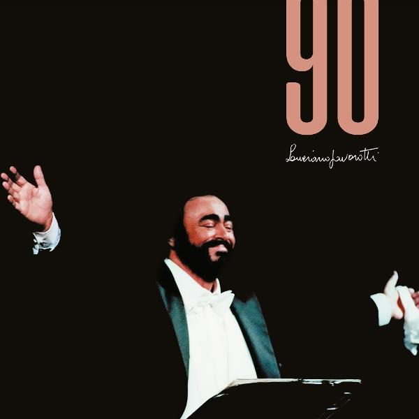 Luciano Pavarotti im Smoking mit Fliege, lächelnd. '90' und 'Luciano Pavarotti' im Text. Schwarzer Hintergrund.