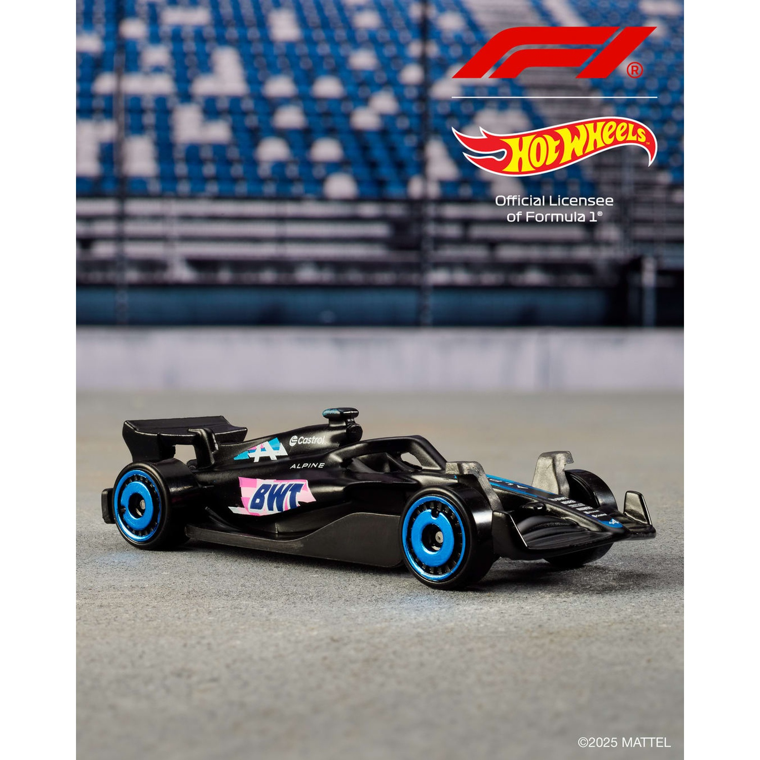 Un'auto nera Hot Wheels Alpine F1 con ruote blu è su una superficie grigia. Lo sfondo ha sedili blu e loghi.