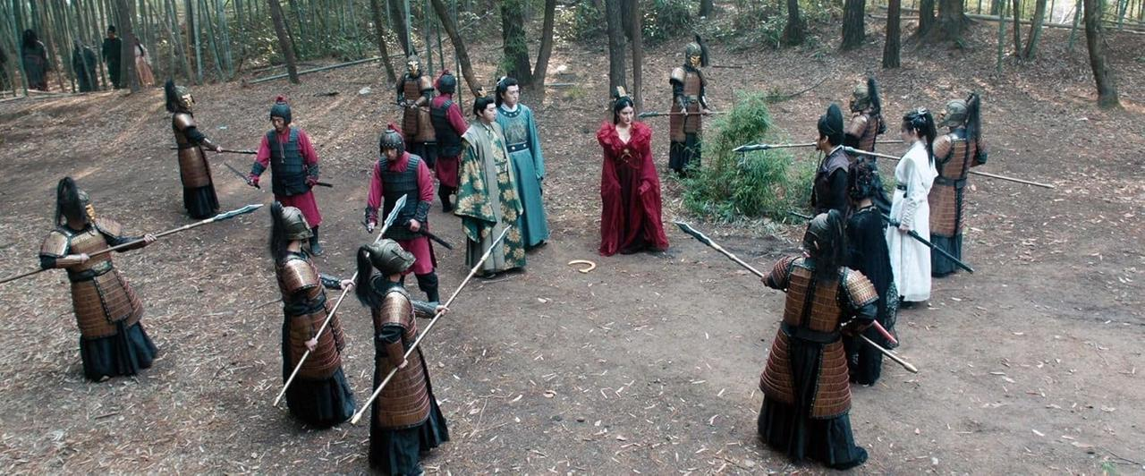 Gruppe von Menschen in alten Kostümen, die Waffen in einem Wald halten. Einige tragen Rüstungen, andere Roben. Ein Kreis von Menschen.