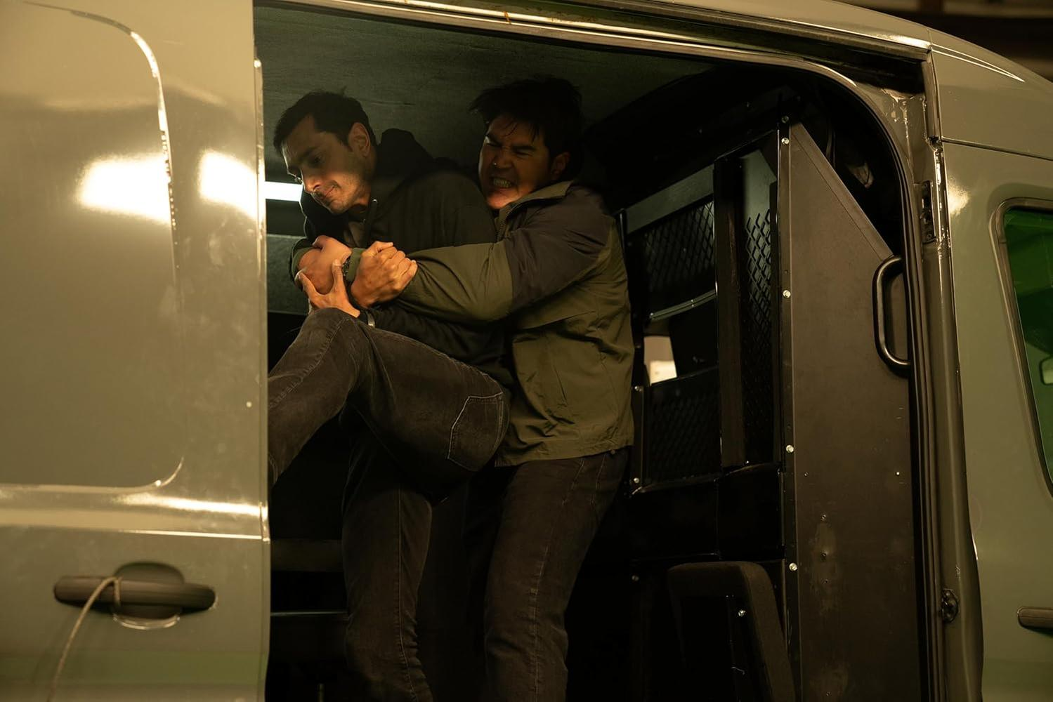 Zwei Männer kämpfen in einem dunklen Transporter. Einer wird vom anderen festgehalten.