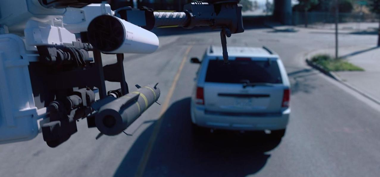 Eine Drohne mit einer Rakete fliegt über einer Straße. Ein silberner SUV fährt auf der Straße. Die Drohne zielt auf das Auto.