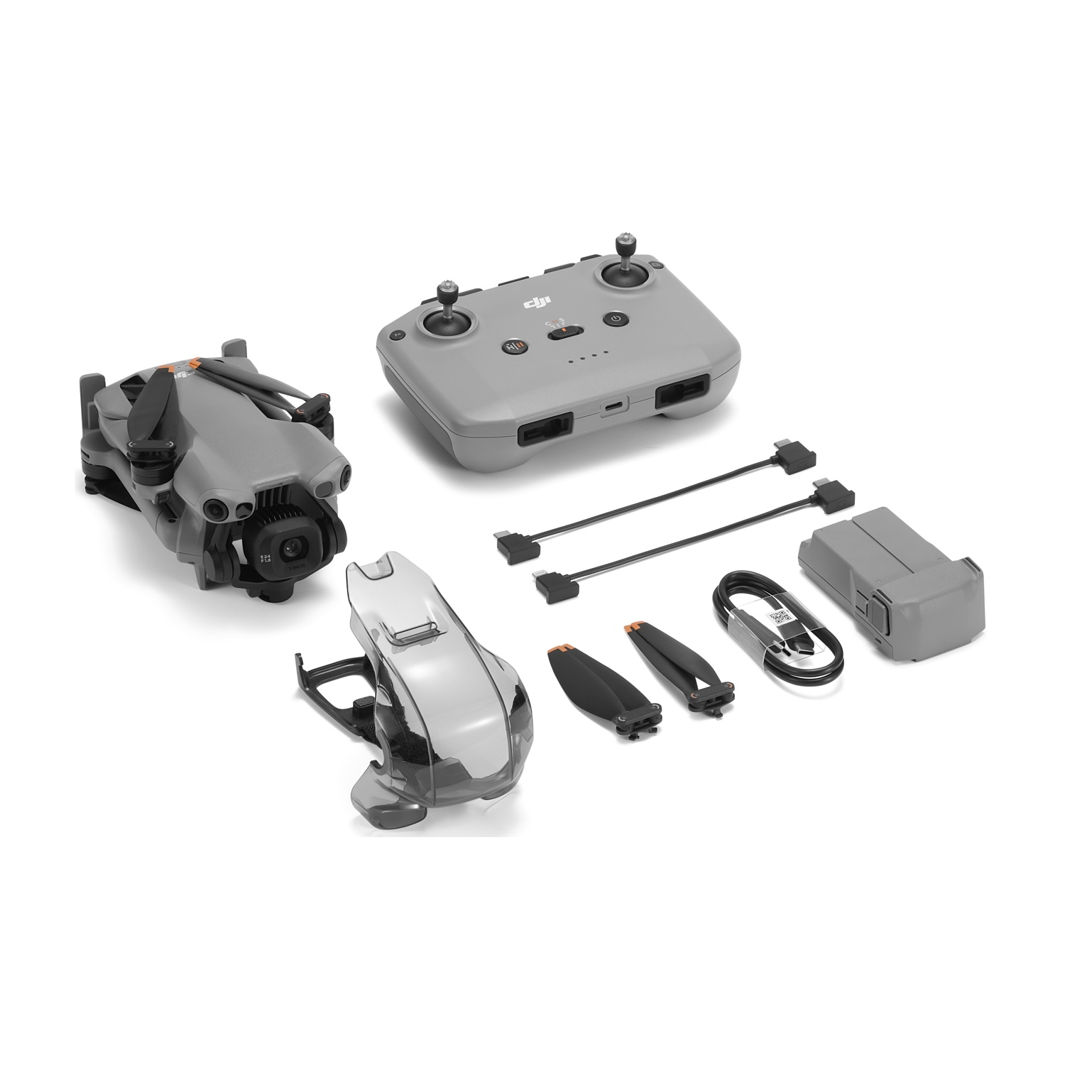 Un kit drone grigio con controller, batteria, eliche, cavi e copriobiettivo, tutto su una superficie bianca.