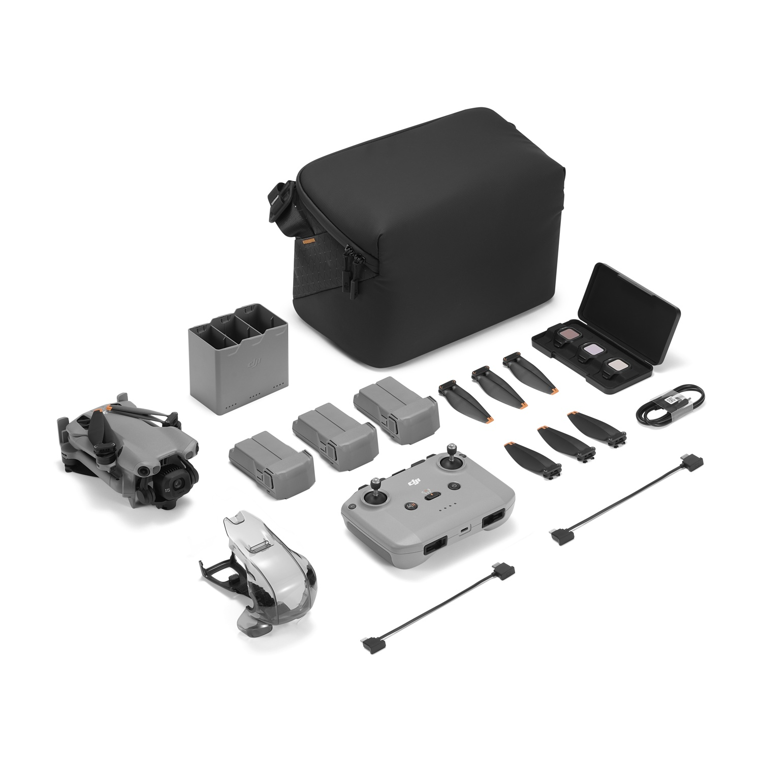 Viene mostrato un kit drone. Include un drone, eliche, batterie, un telecomando, una borsa per il trasporto e altri accessori, tutto su sfondo bianco.