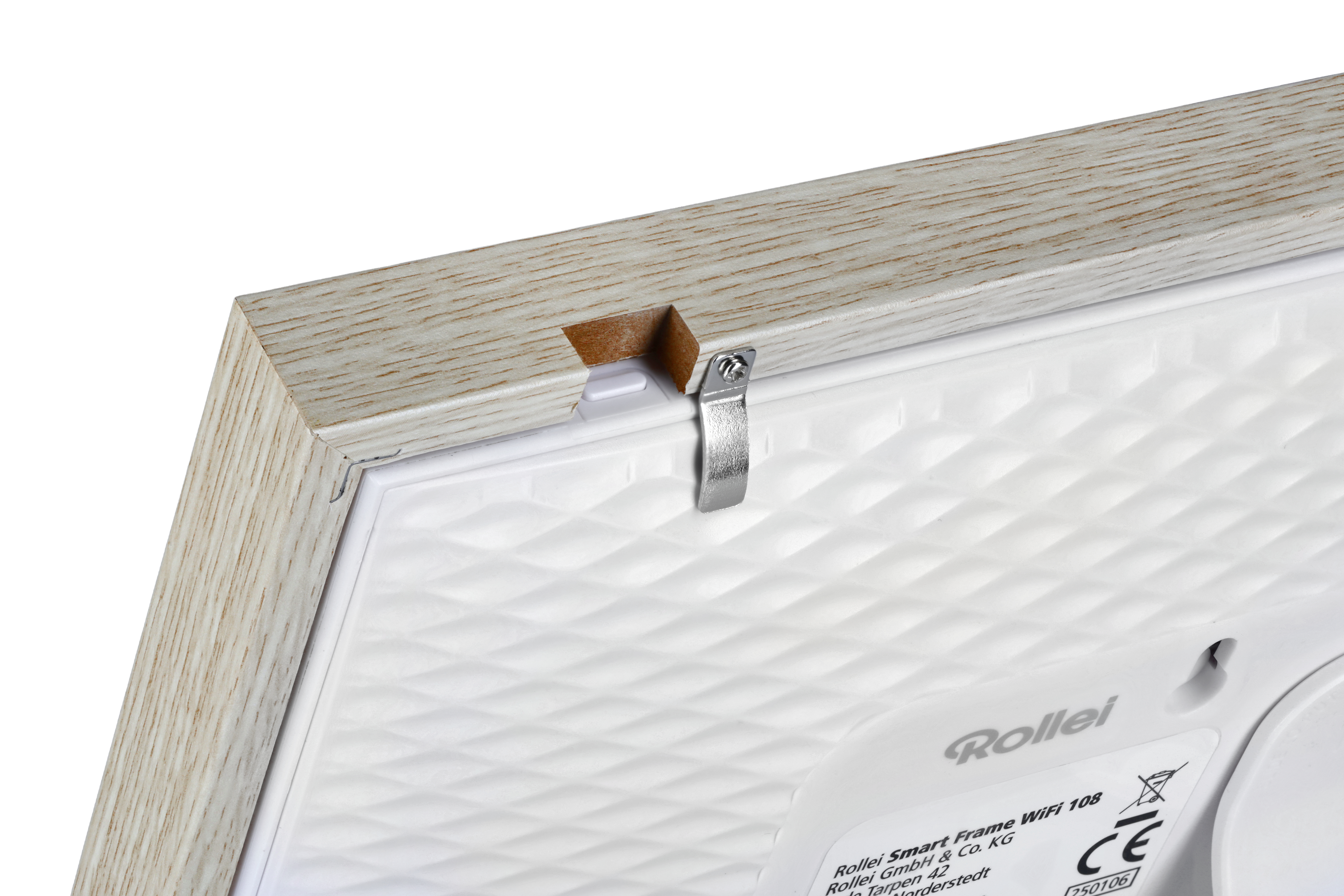 Nahaufnahme einer Holzeckrahmens mit Metallclip. Der Rahmen umgibt eine weiße, strukturierte Oberfläche mit 'Rollei' Logo.