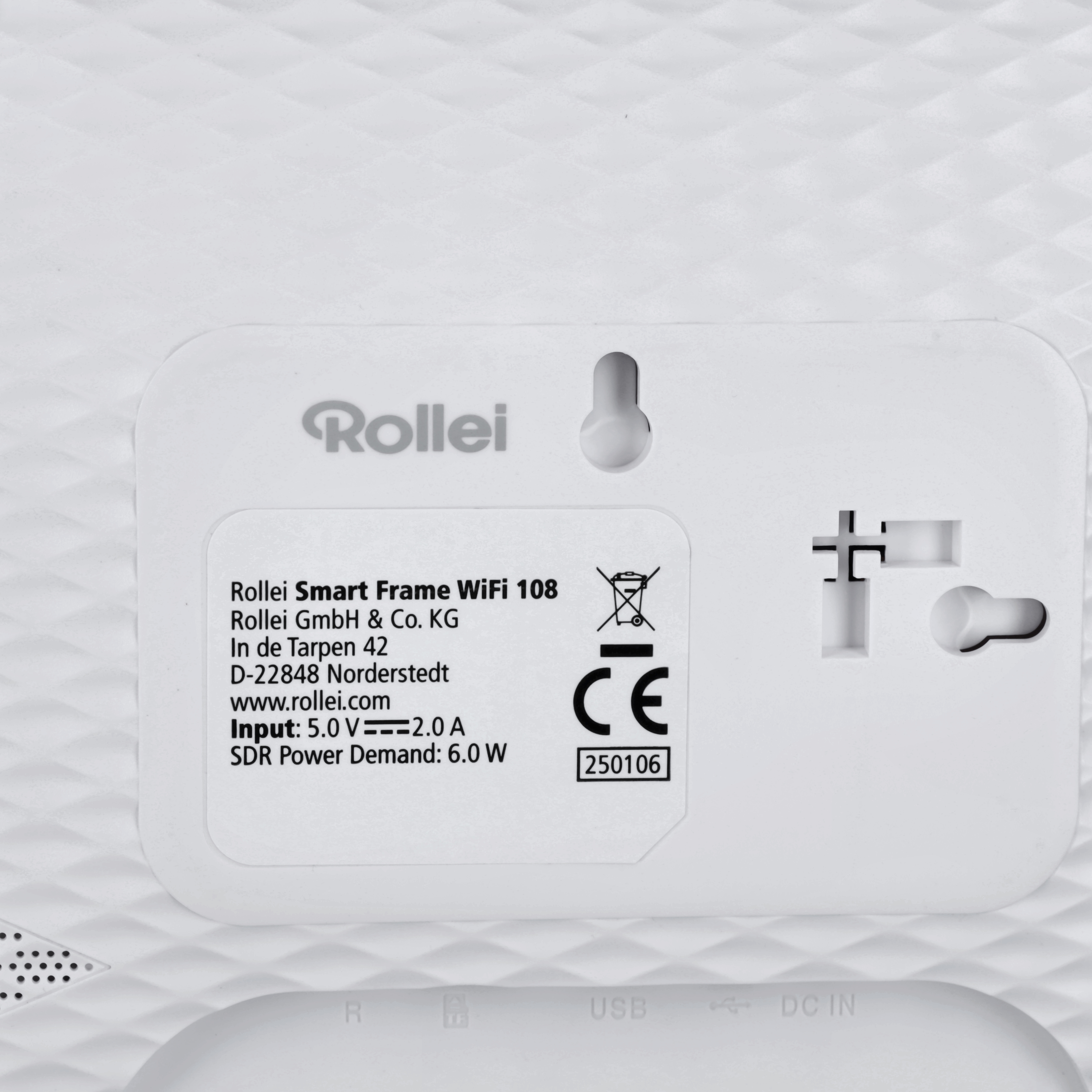 Ein weißes Gerät mit Rollei-Logo und Produktinformationen vor strukturiertem, weißen Hintergrund.
