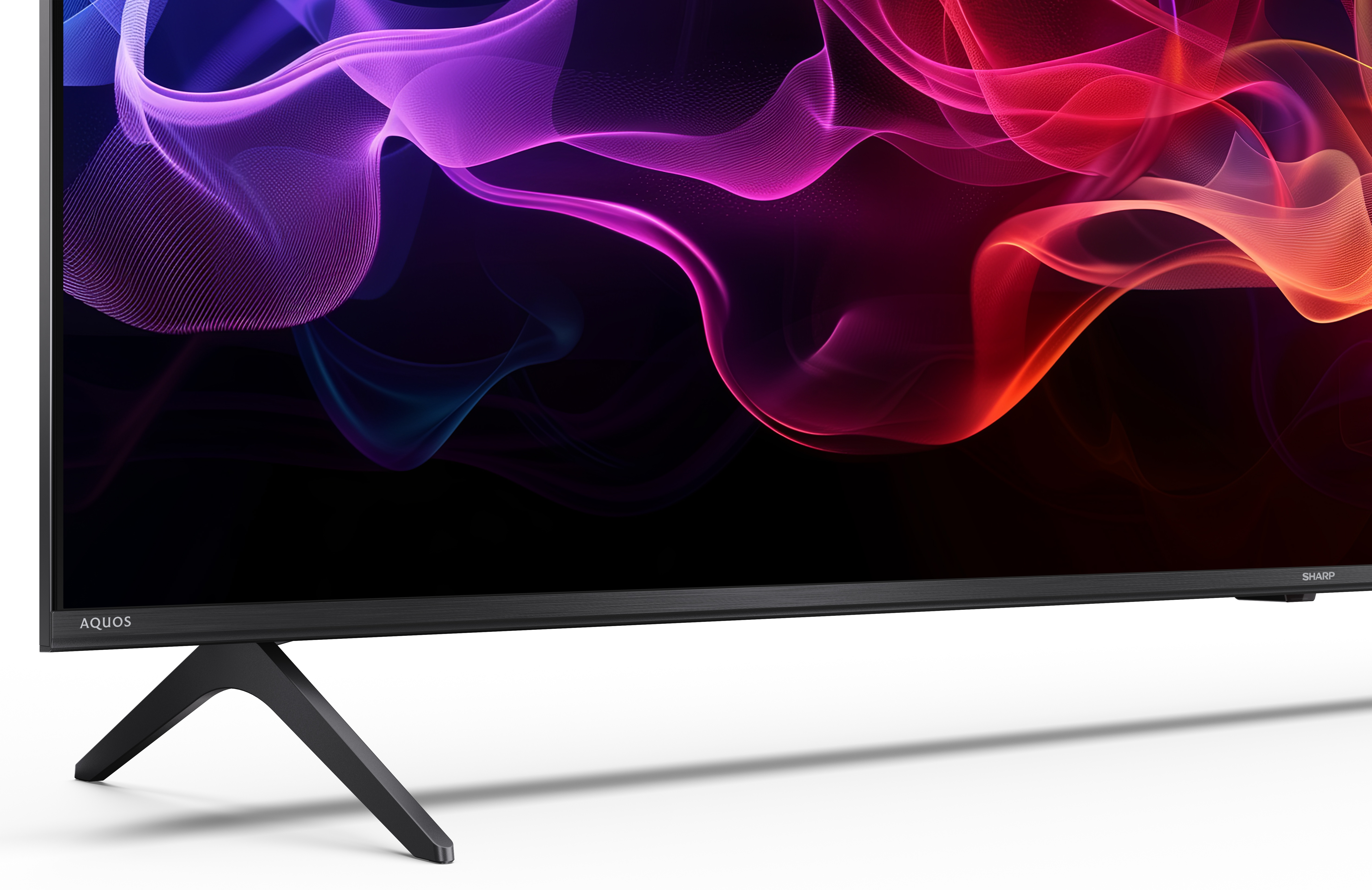 Telewizor Sharp Aquos z czarną ramą i podstawą. Ekran wyświetla kolorowe, abstrakcyjne kształty.