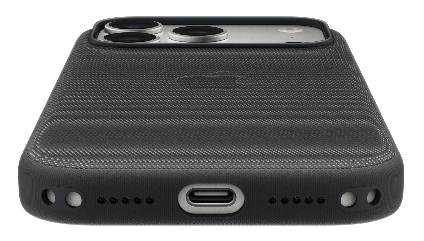 Zbliżenie na ciemnoszarą obudowę telefonu. Ma teksturowaną powierzchnię z logo Apple. Na dole znajduje się port ładowania i otwory głośnikowe.