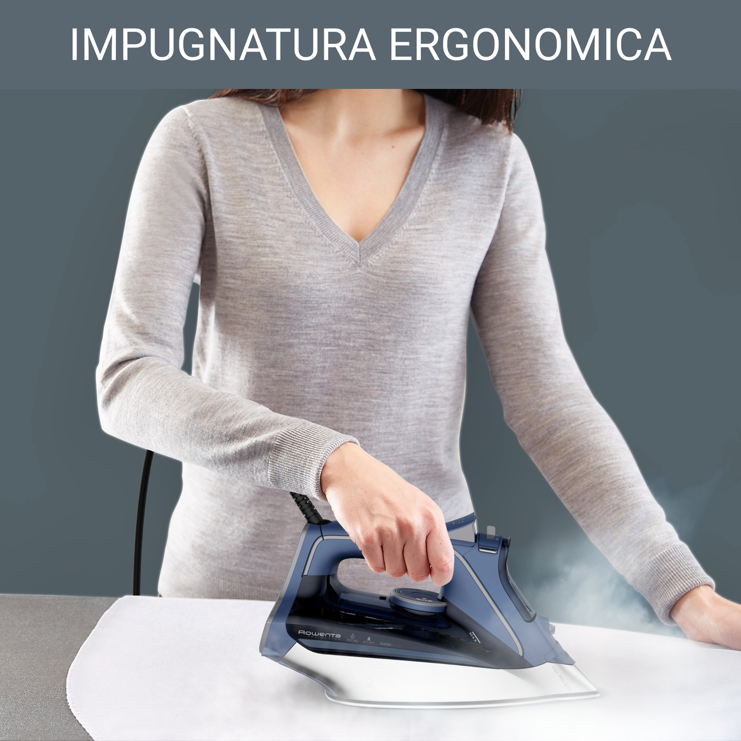 Una donna stira un tessuto bianco con un ferro da stiro blu. Il ferro emette vapore. Lo sfondo è un muro grigio.