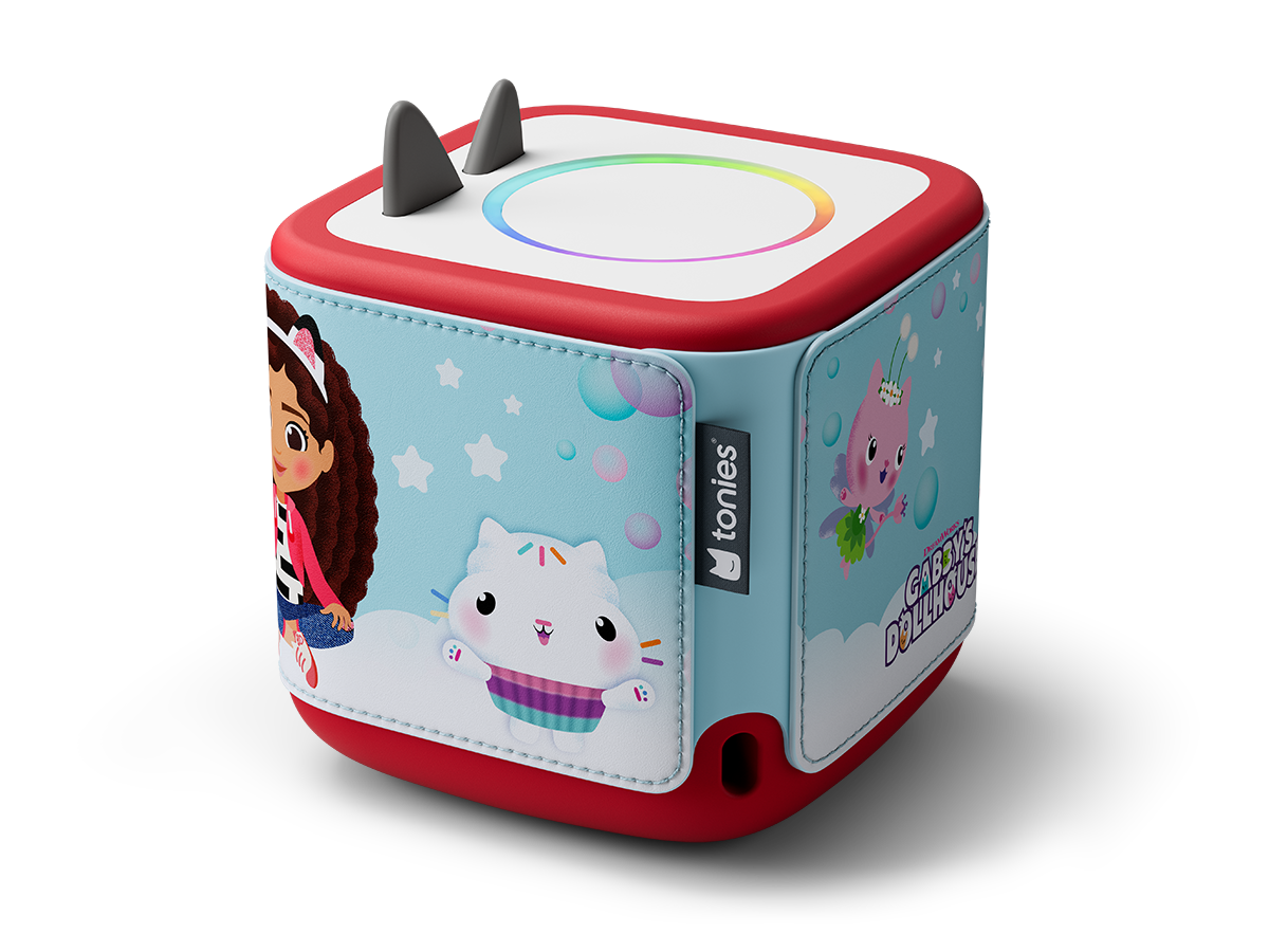 Un jouet cube rouge et bleu avec les personnages de Gabby's Dollhouse. Il a deux oreilles grises et une lumière colorée sur le dessus.