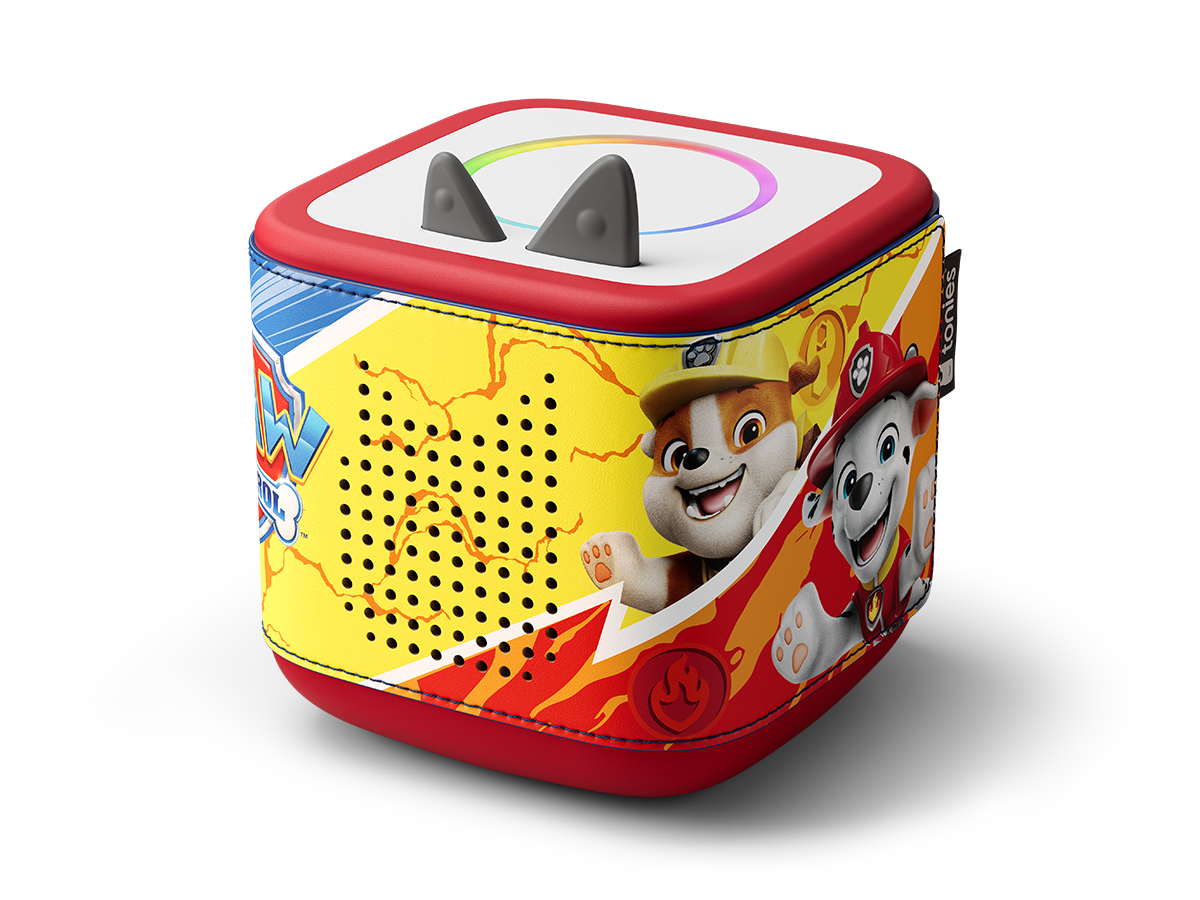 Un Toniebox di Paw Patrol. È un cubo rosso, giallo e blu con personaggi di Paw Patrol. Orecchie grigie e un anello luminoso in alto.