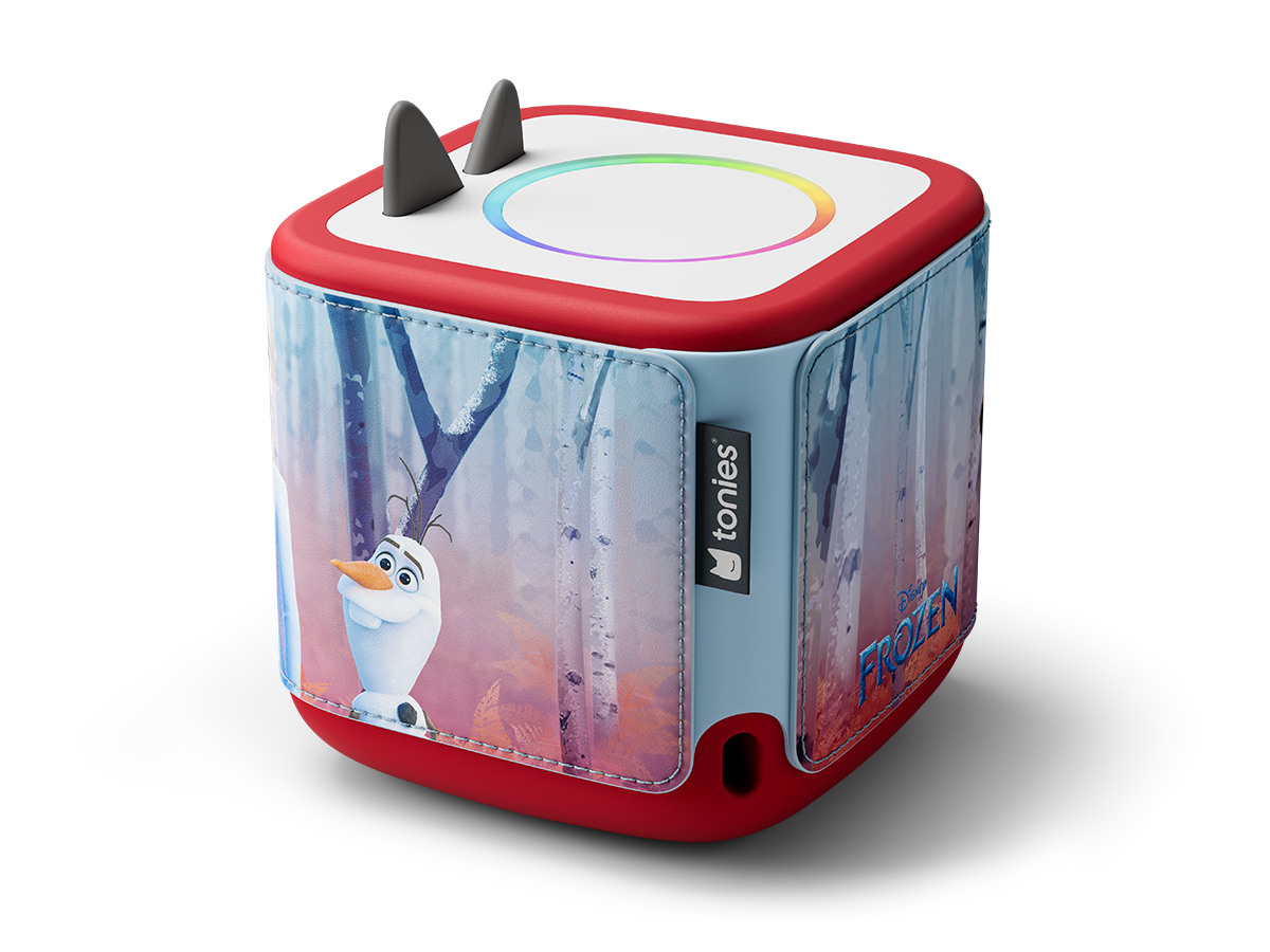 Une Toniebox sur le thème de La Reine des Neiges. C'est un cube avec Olaf, une base rouge, des côtés bleus et une lumière arc-en-ciel au-dessus. Deux petites cornes grises sont visibles.