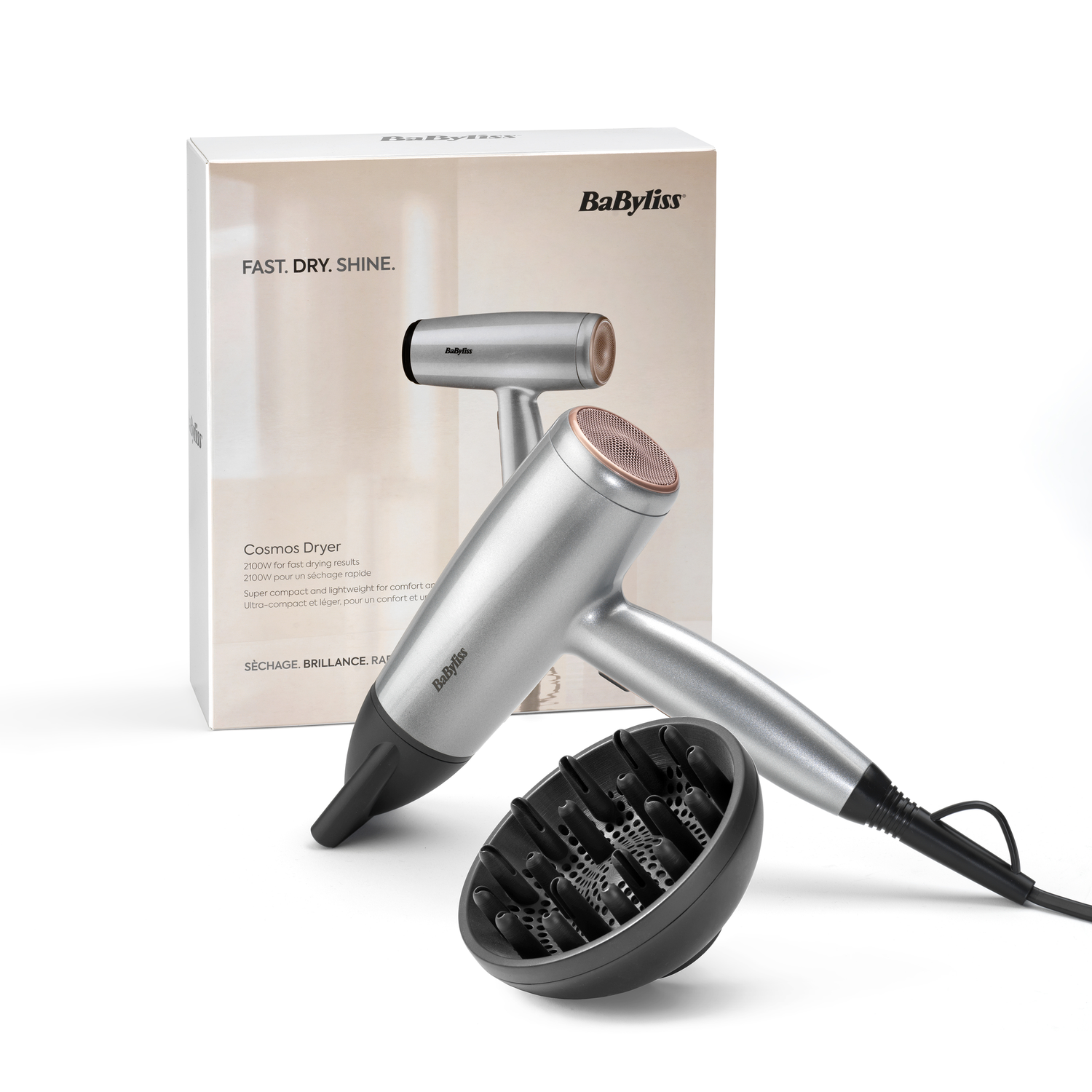 A silver Babyliss hair dryer with a rose gold nozzle and black diffuser, beside its box. The box says 'Fast. Dry. Shine.'