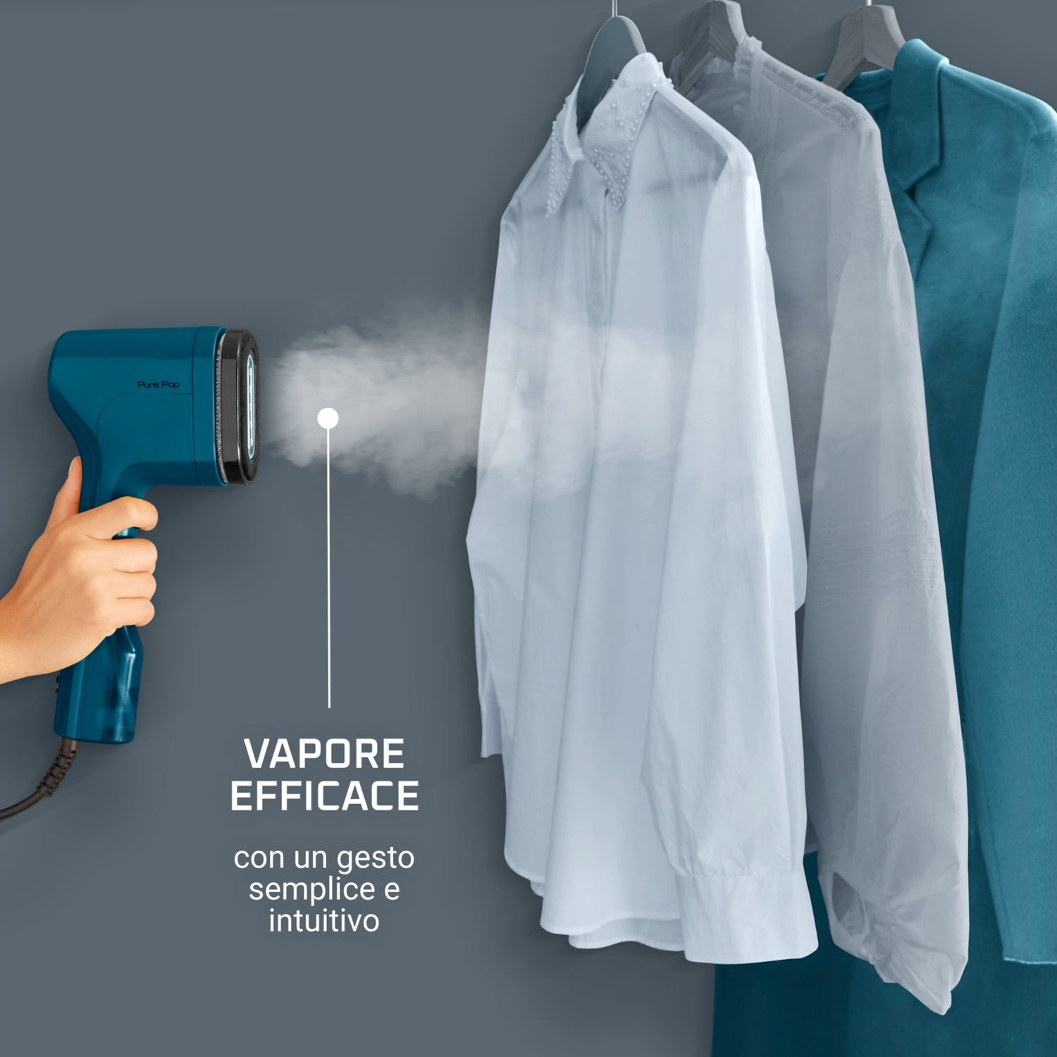 Una mano tiene uno vaporizzatore turchese, che vaporizza una camicia bianca. Altri vestiti sono appesi su un attaccapanni sullo sfondo. Muro grigio.