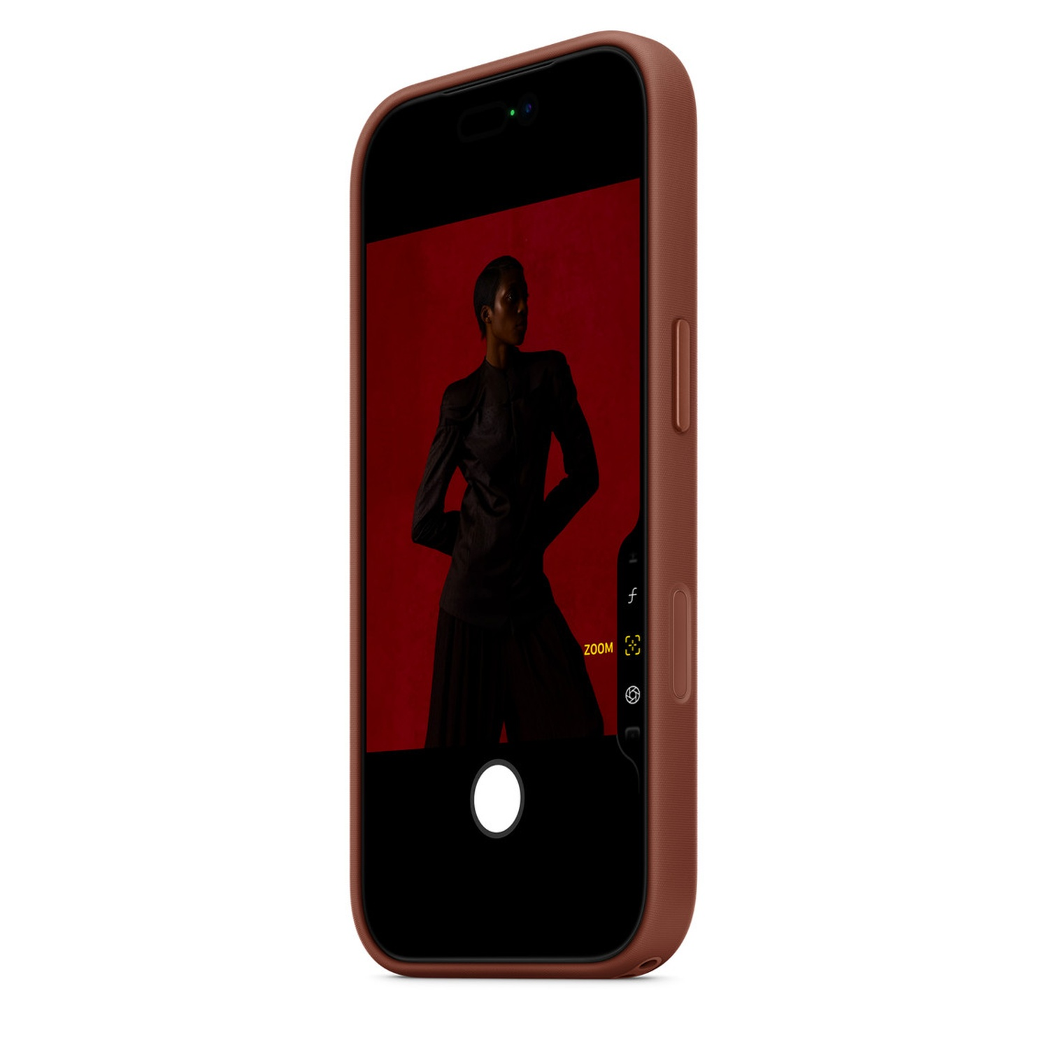 Un téléphone affiche une photo d'une personne en vêtements sombres sur fond rouge. Le téléphone est dans un étui marron.