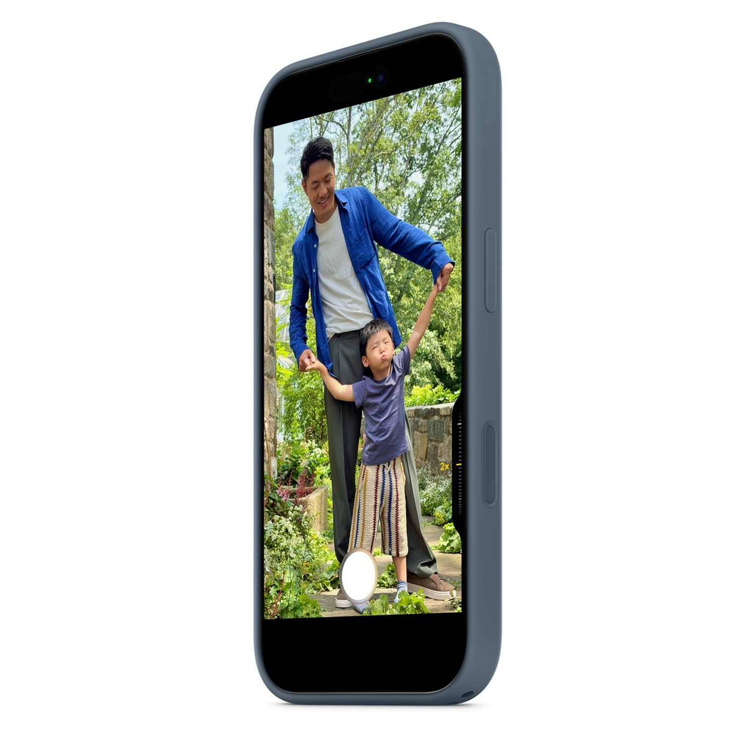 Father and child holding hands, captured on a phone screen. The scene shows a garden, with the father smiling, and the child looking up.