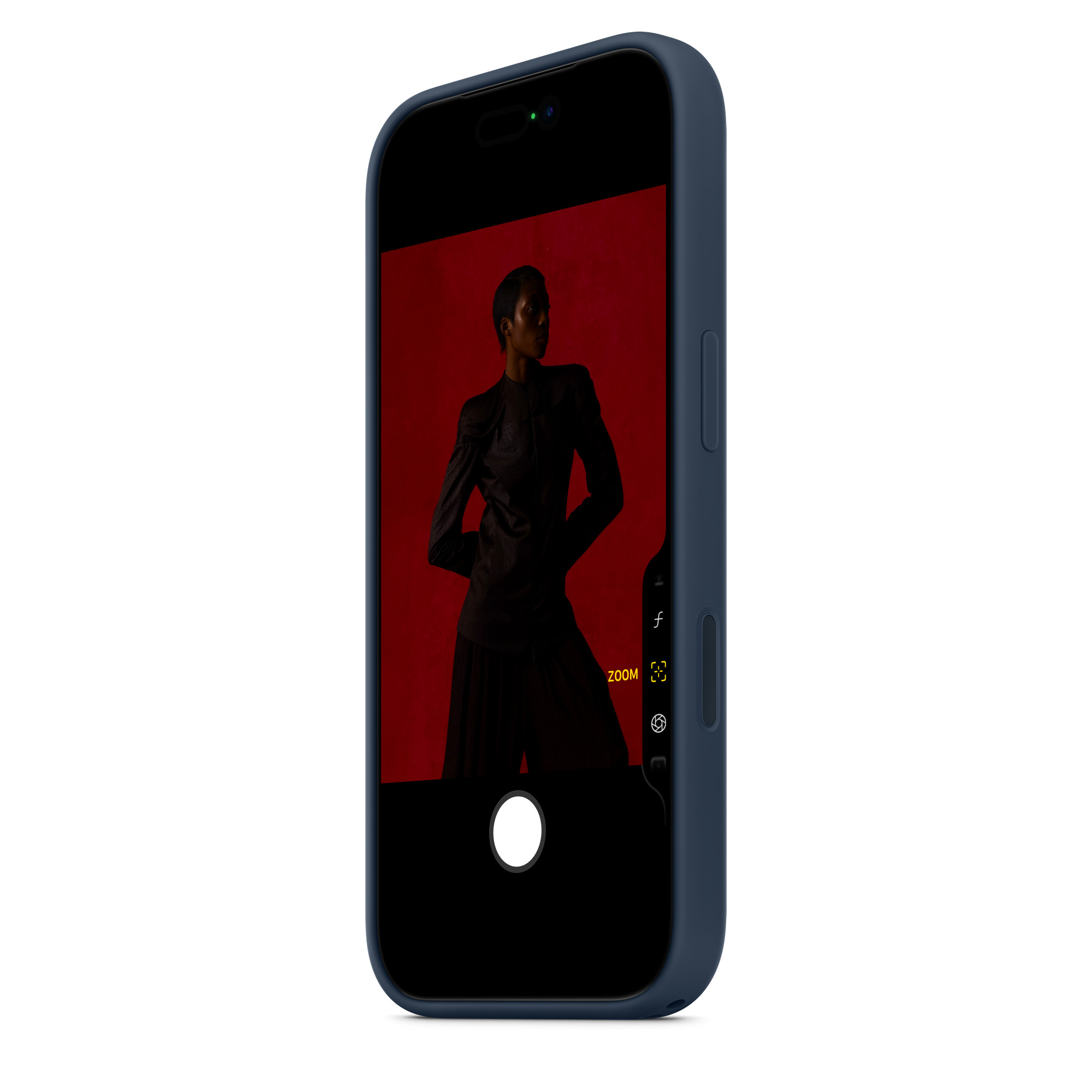 Telefon z ciemnym ekranem wyświetla osobę w ciemnych ubraniach na czerwonym tle. Telefon ma niebieskie etui.