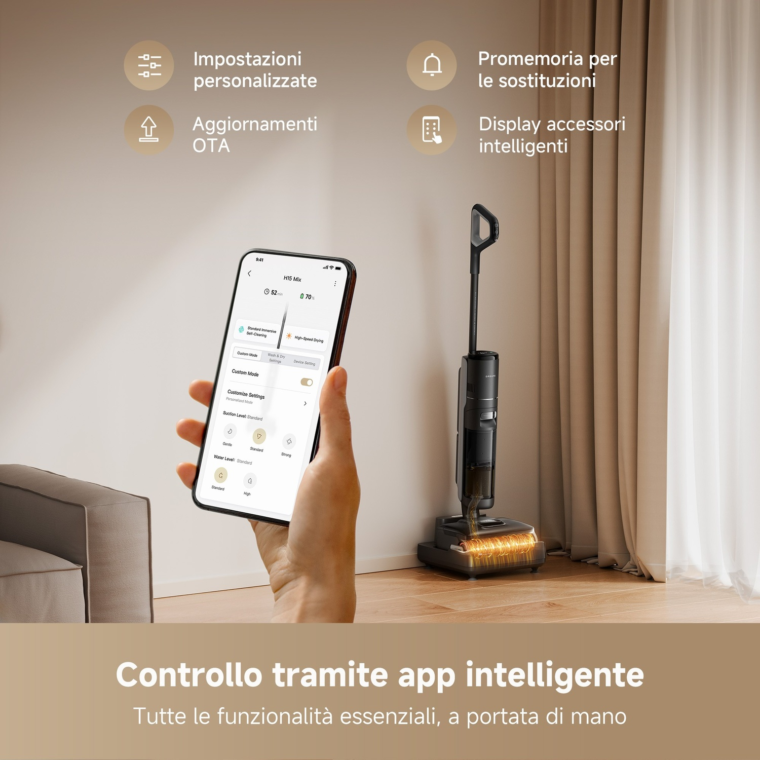 Una persona tiene in mano uno smartphone che mostra un'app che controlla un aspirapolvere nero. L'aspirapolvere è su un pavimento in legno. Lo sfondo include una tenda beige.