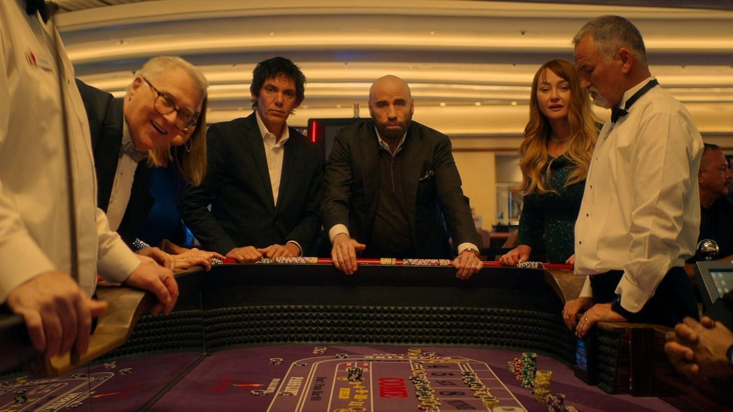 Leute an einem Casinotisch. Männer und Frauen lehnen sich an den Tisch und schauen interessiert auf das Würfelspiel.