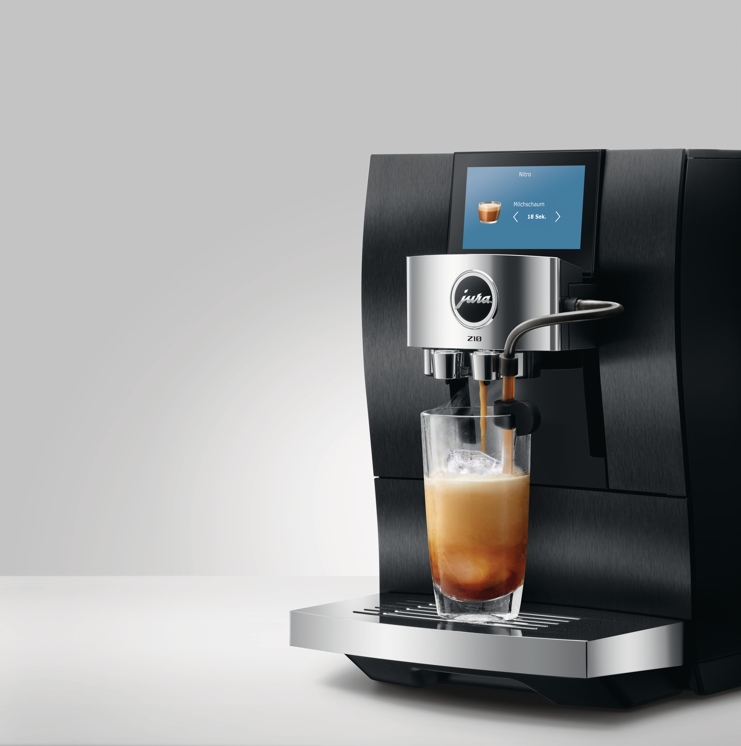Eine schwarze Jura-Kaffeemaschine gießt Kaffee in ein Glas mit Eis. Die Maschine hat einen Bildschirm mit der Aufschrift 'Nitro'.