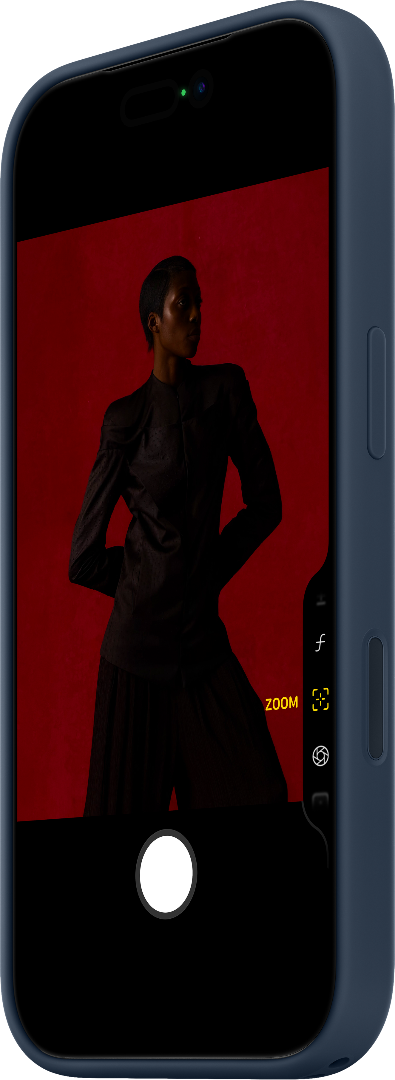 Un telefono mostra una persona vestita di scuro su sfondo rosso. Il telefono ha una custodia blu e controlli della fotocamera.