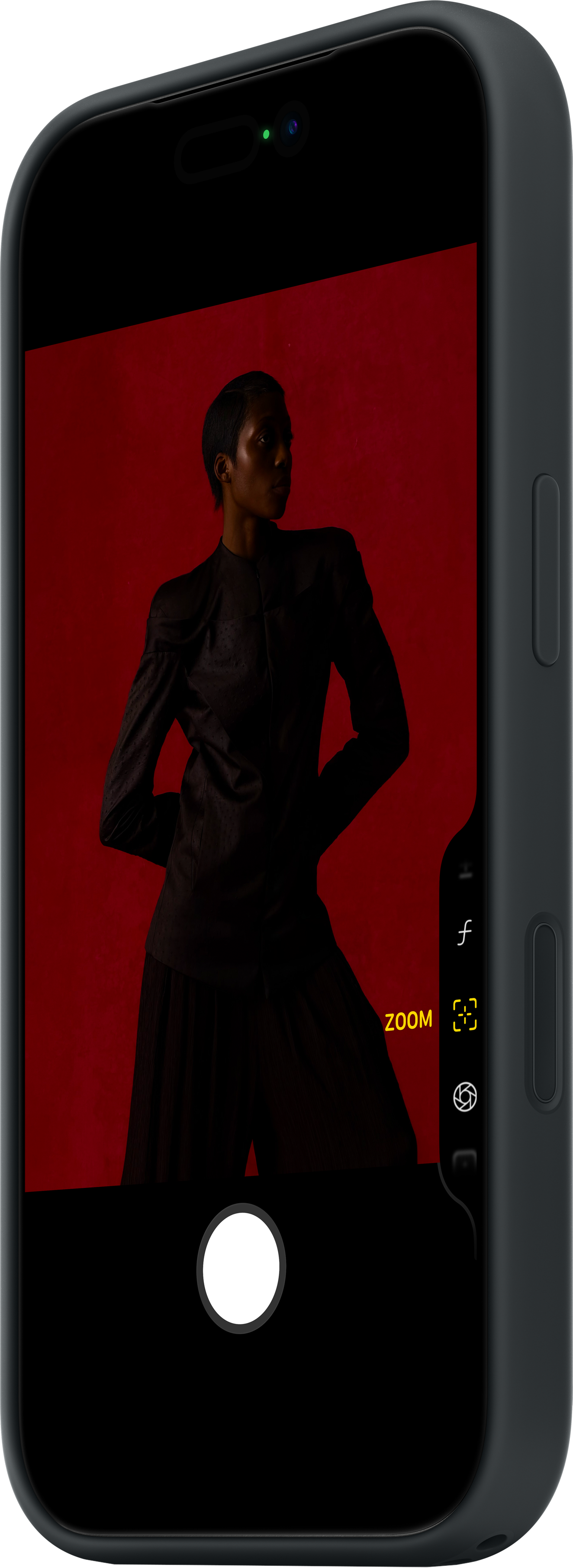 Una persona vestita di scuro è inquadrata sullo schermo di un telefono, su sfondo rosso. Controlli del telefono visibili.