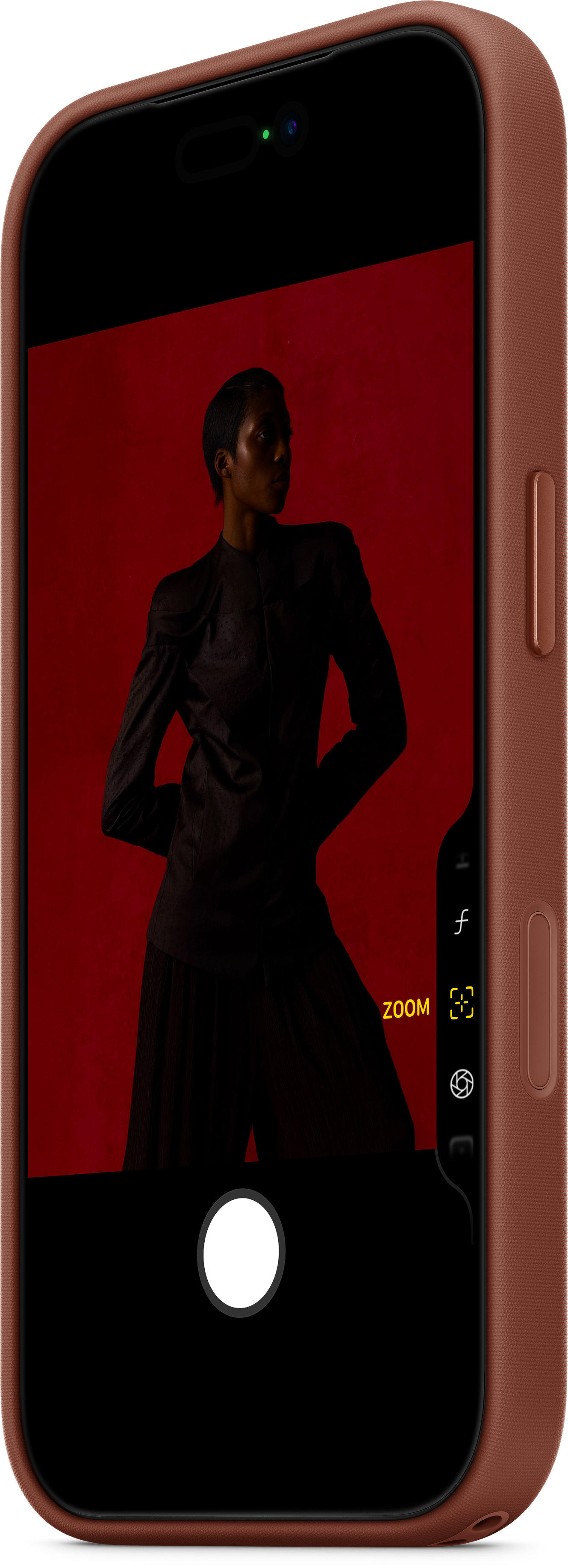 Eine Person steht vor rotem Hintergrund, aufgenommen auf einem Telefonbildschirm. Das Telefon hat eine braune Hülle, Zoom und Einstellungen sind sichtbar.