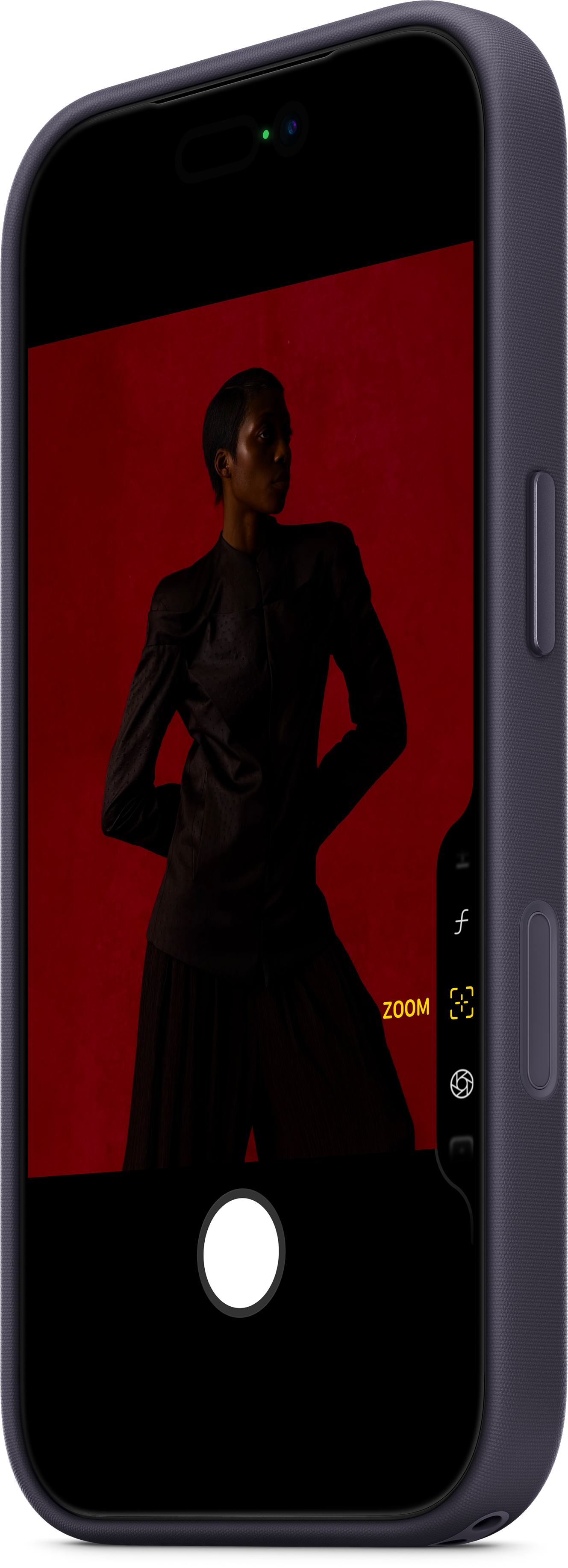 Eine Person in einem schwarzen Anzug steht vor rotem Hintergrund, aufgenommen auf einem Telefonbildschirm. Zoom- und Kamerasteuerung.