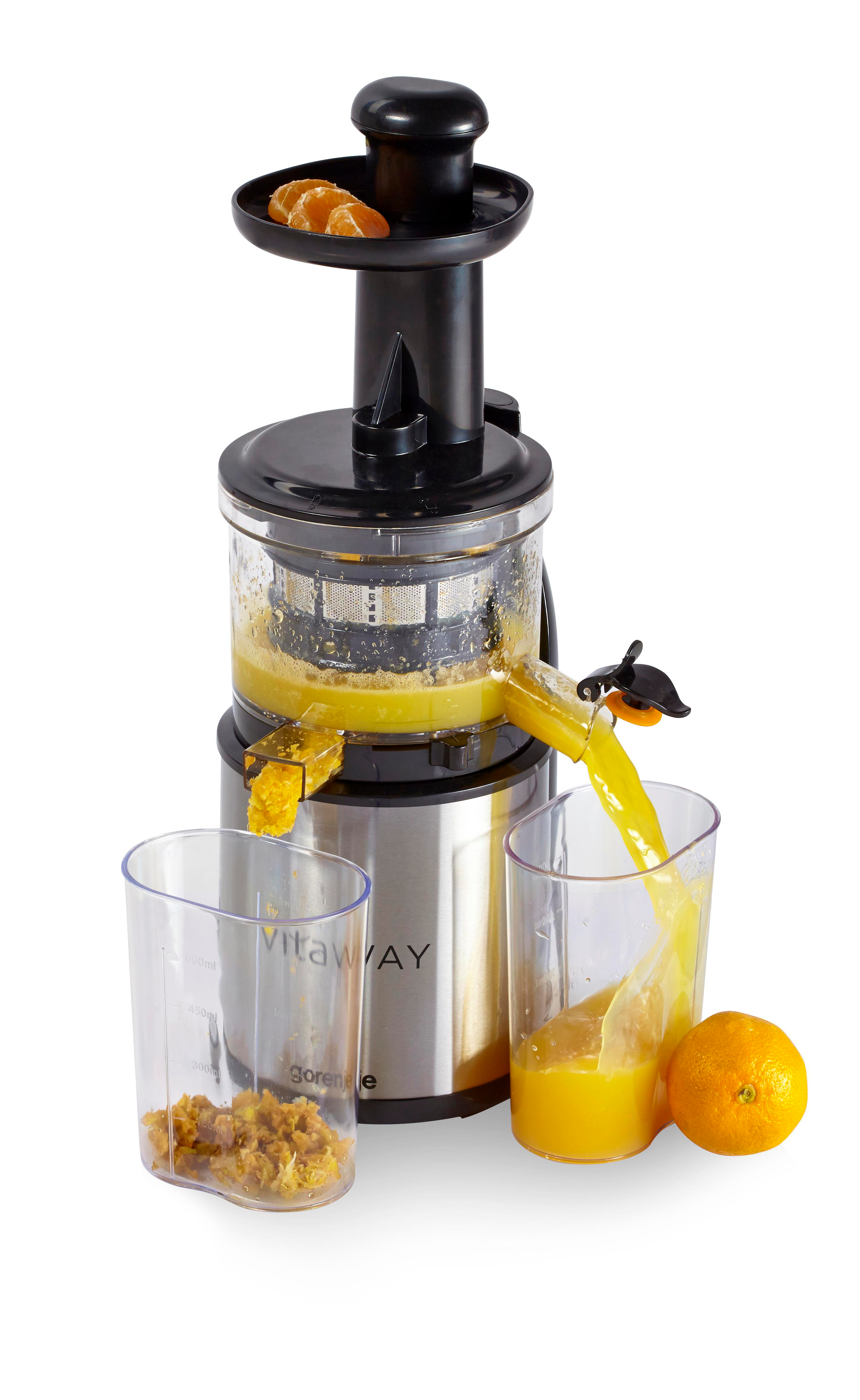 Entsafter mit Orangensaft, der in ein Glas gegossen wird. Orangenstücke oben. Eine ganze Orange liegt daneben.