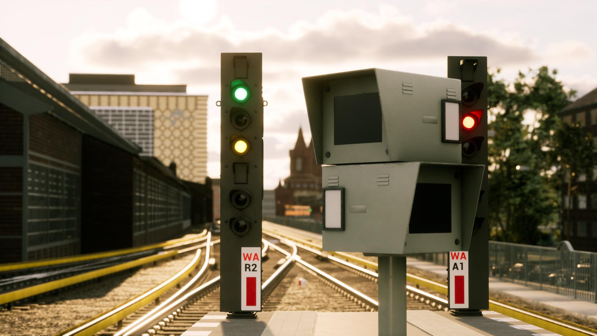 Zwei Signale an einem Bahnsteig mit grünen und gelben Lichtern, rote Lichter. Gebäude im Hintergrund.