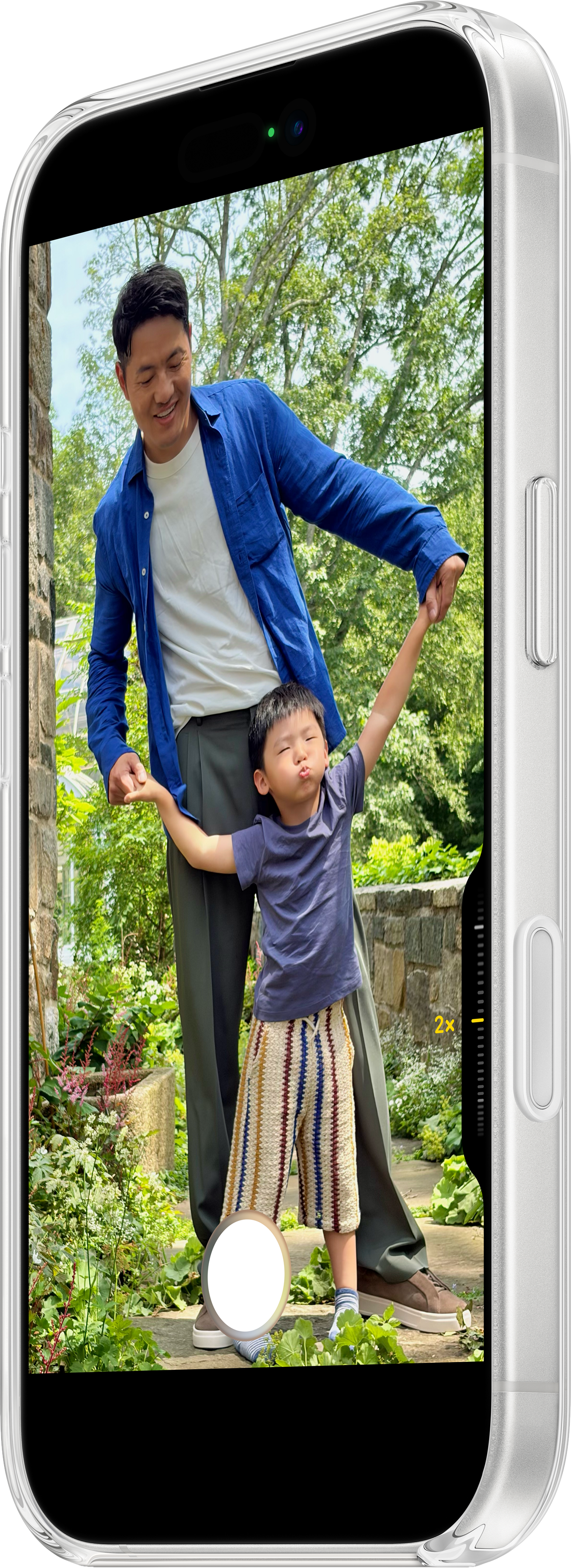 Un homme et un enfant dans un jardin. L'enfant a les bras tendus. L'homme porte une chemise bleue et l'enfant une chemise bleue.