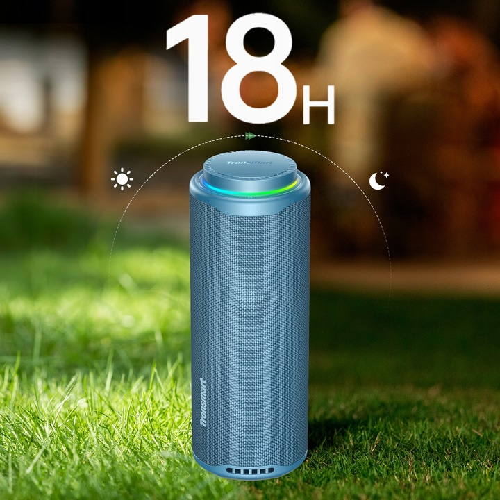 Niebieski głośnik Tronsmart na trawie. Obraz pokazuje 18 godzin pracy na baterii. Ikony słońca i księżyca. Rozmyte tło z zielenią i brązem.