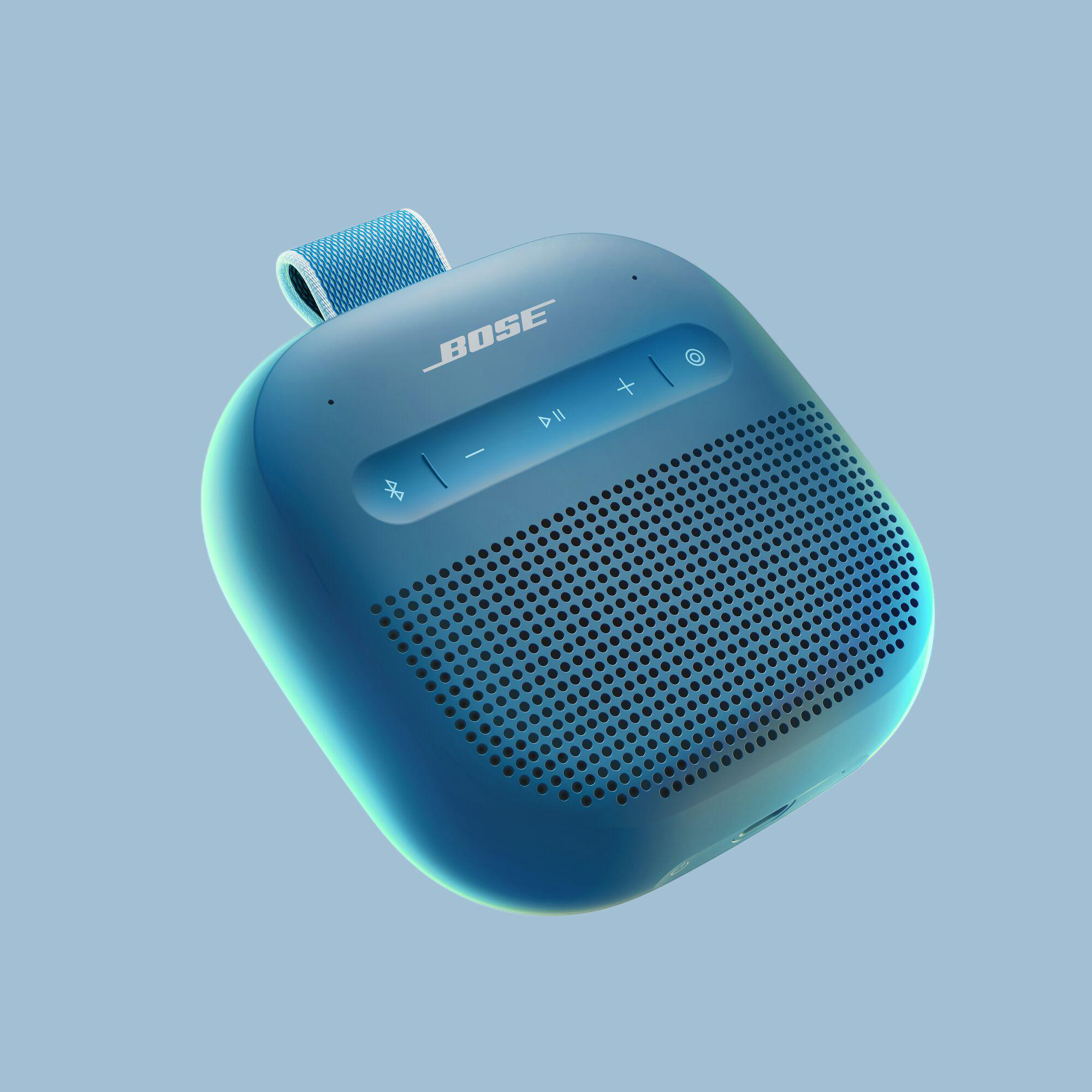 Ein blauer tragbarer Bose-Lautsprecher. Er hat Bedientasten und einen Griff. Der Hintergrund ist hellblau.