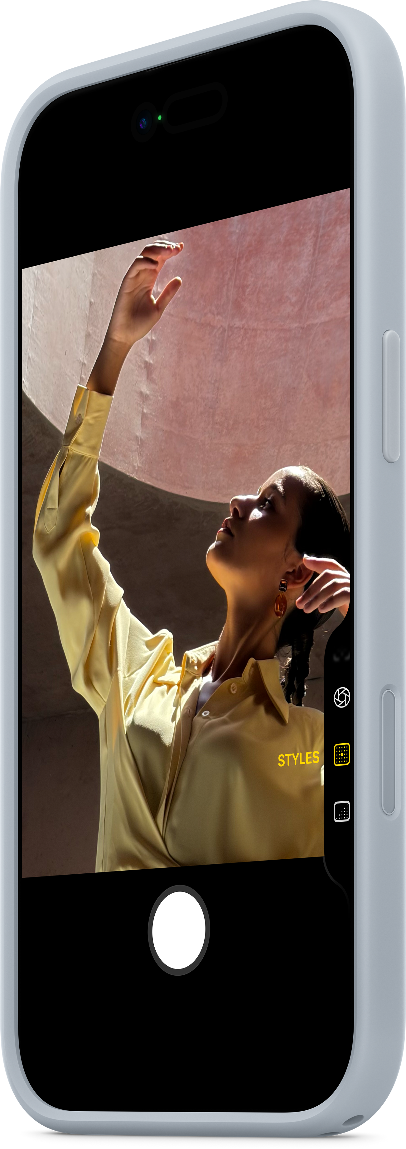 Une personne en chemise jaune lève la main vers la lumière. L'image est encadrée dans un téléphone.