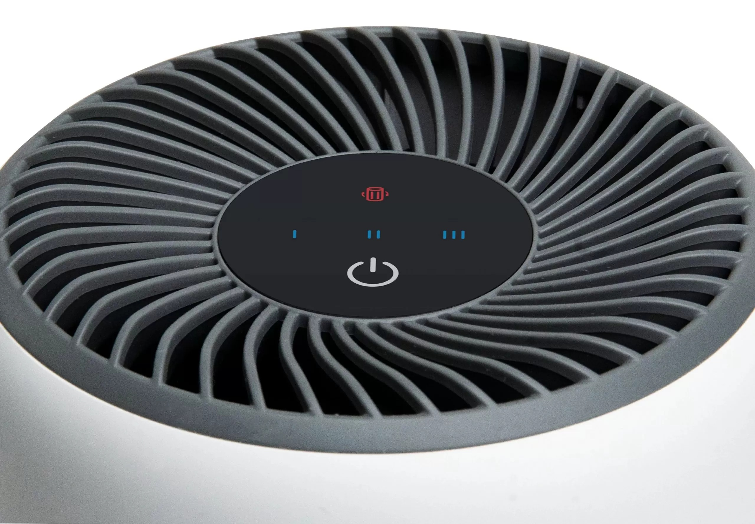 Zbliżenie oczyszczacza powietrza. Szare łopatki wentylatora otaczają czarne centrum z przyciskiem zasilania i ikonami.