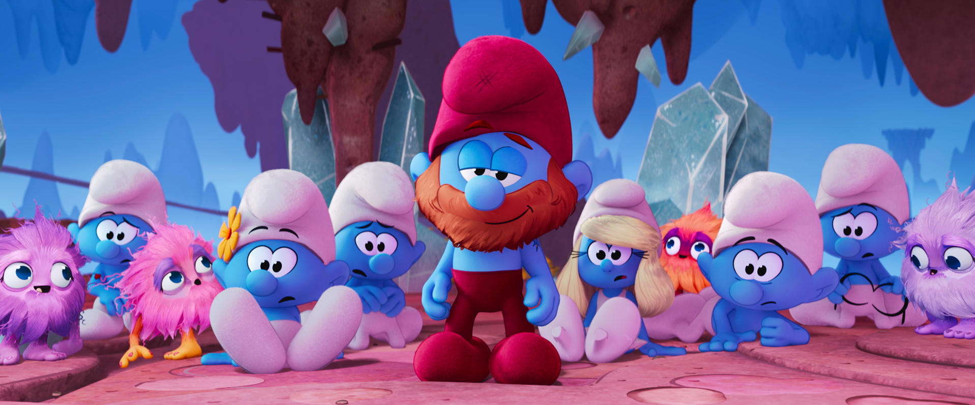 Eine Gruppe Schlümpfe und pelzige Kreaturen stehen zusammen. Papa Schlumpf steht in der Mitte. Der Hintergrund hat blaue und braune Felsformationen.