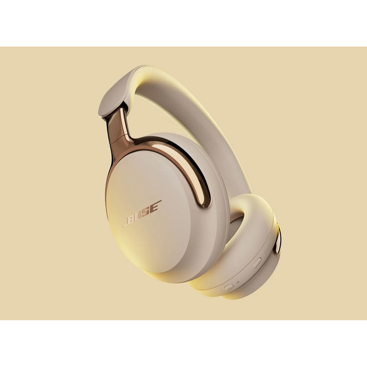 Beige Bose headphones on a yellow background. The headphones have gold accents and the Bose logo.