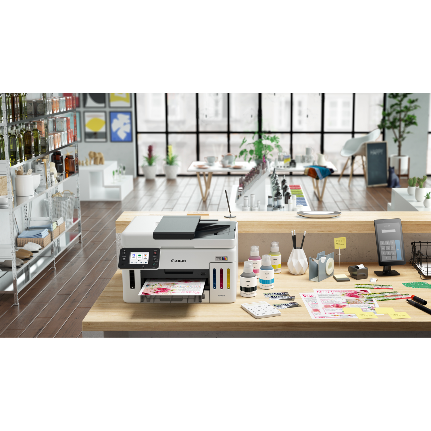 A Canon printer sits on a wooden counter. Ink bottles, a calculator, and other office supplies are scattered around.