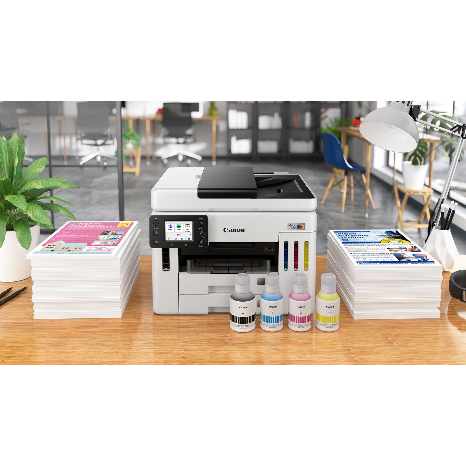 A Canon printer with ink bottles and stacks of papers on a wooden desk. Office background with a lamp and plants.
